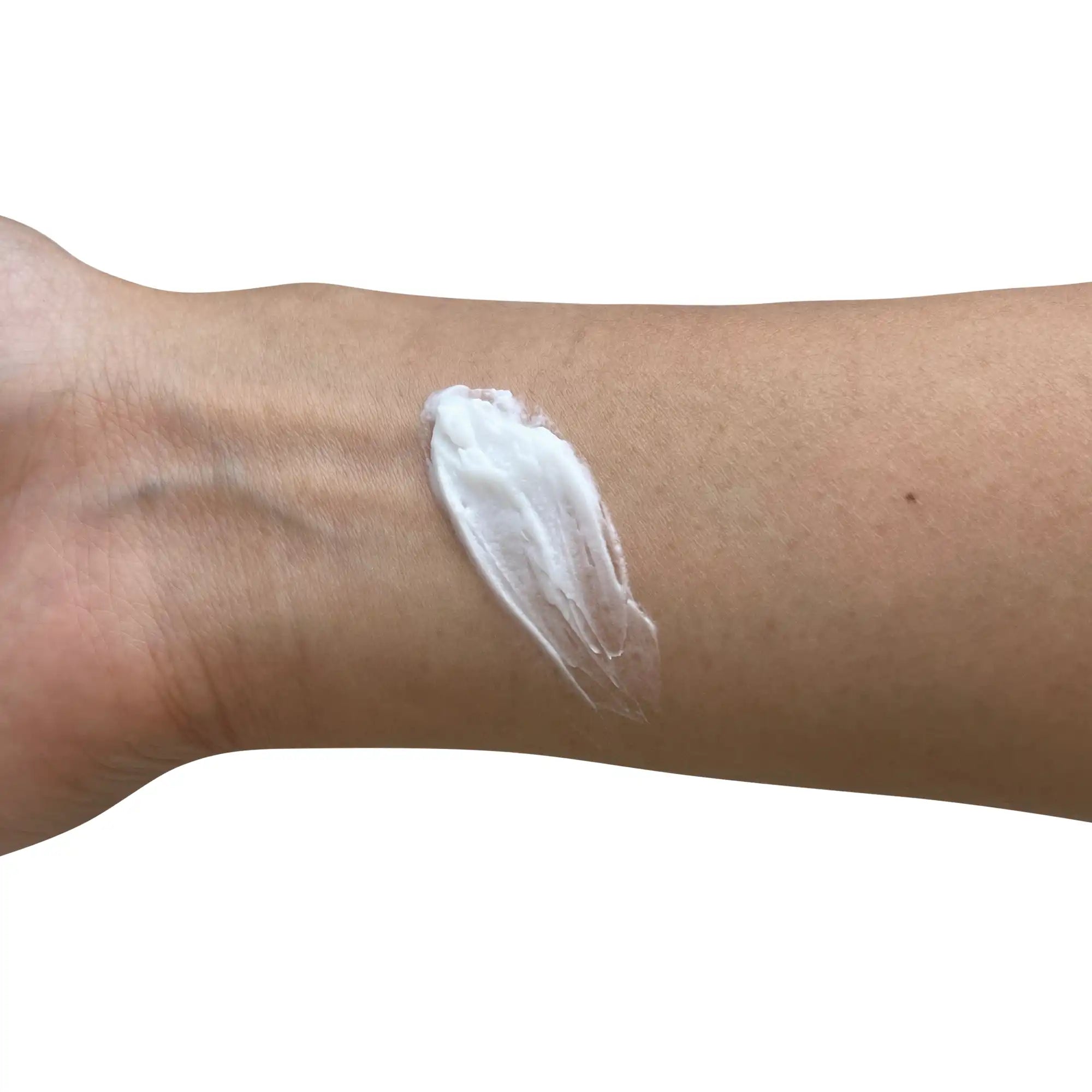 A white cream is swatched on a person's forearm.
