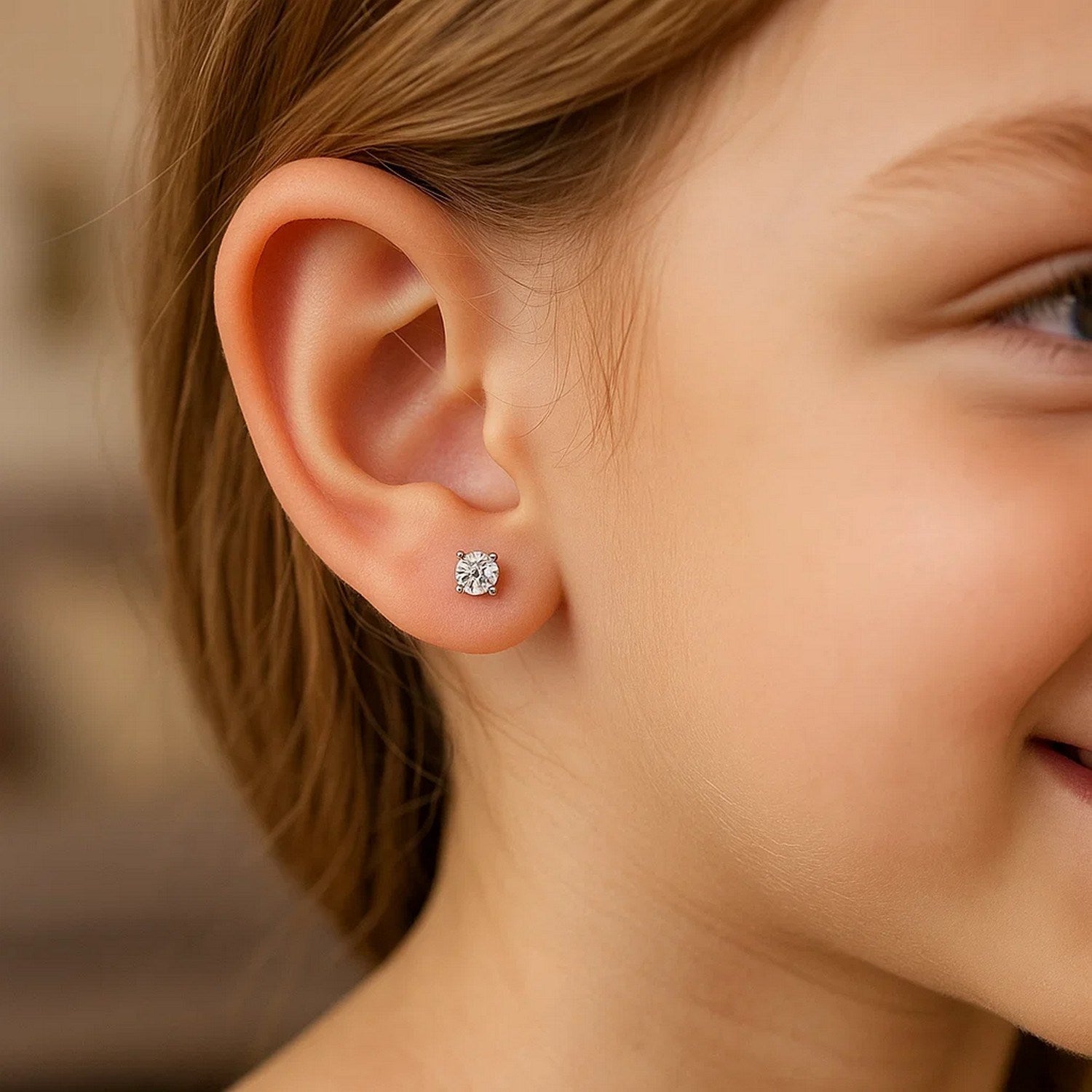 Sterling silver stud earrings with 3mm faceted white cubic zirconia on a child's ear.