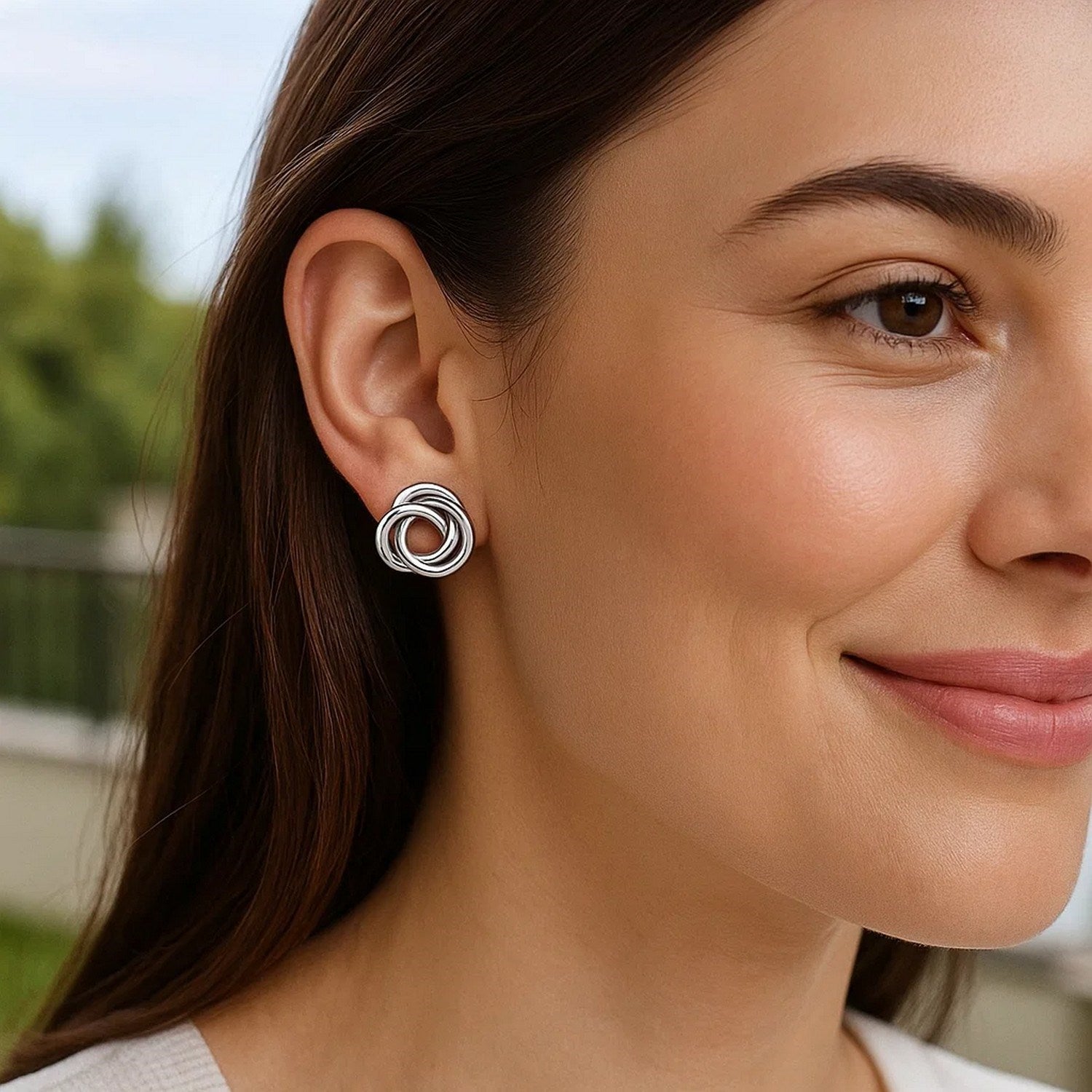 Polished open love knot sterling silver earrings on a woman's ear.