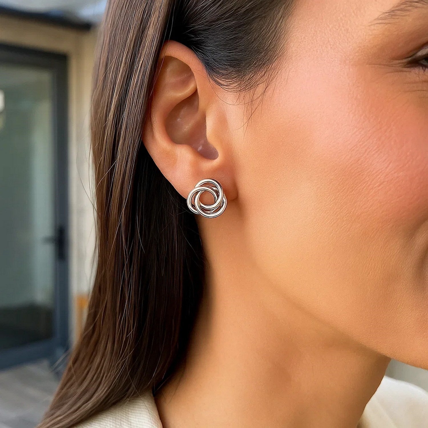 Polished open love knot earrings in sterling silver on a woman's ear.