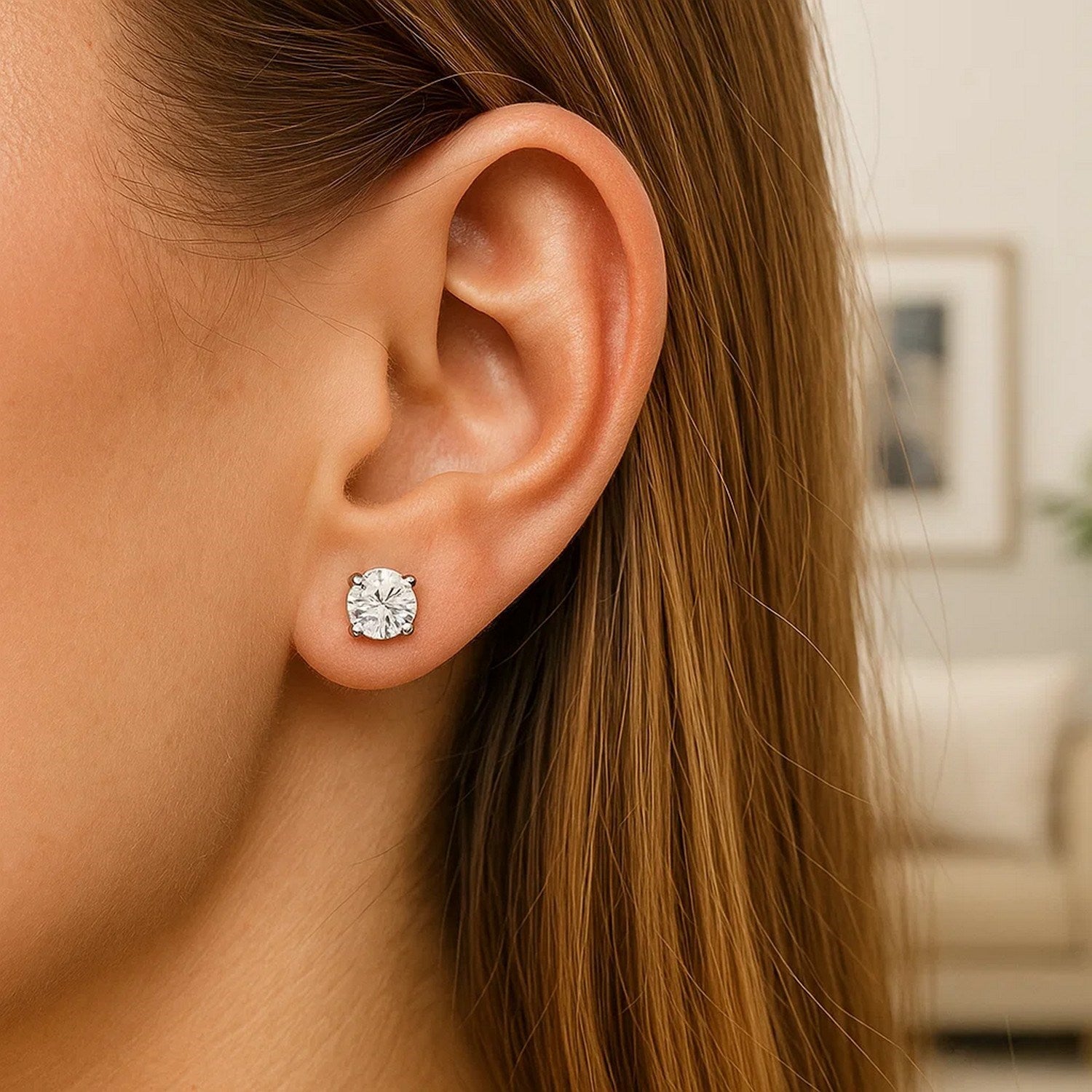Sterling silver stud earring with a round, white cubic zirconia on a woman's ear.