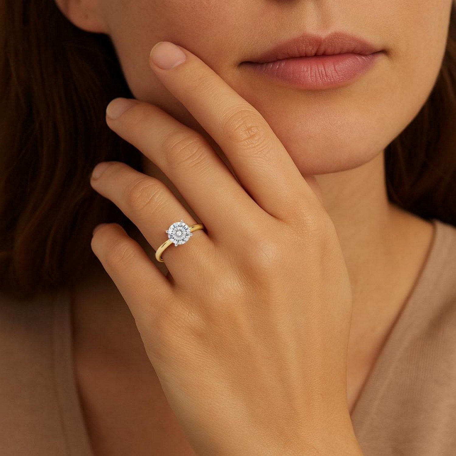 A woman wears a yellow gold solitaire ring with a round diamond on her left ring finger.