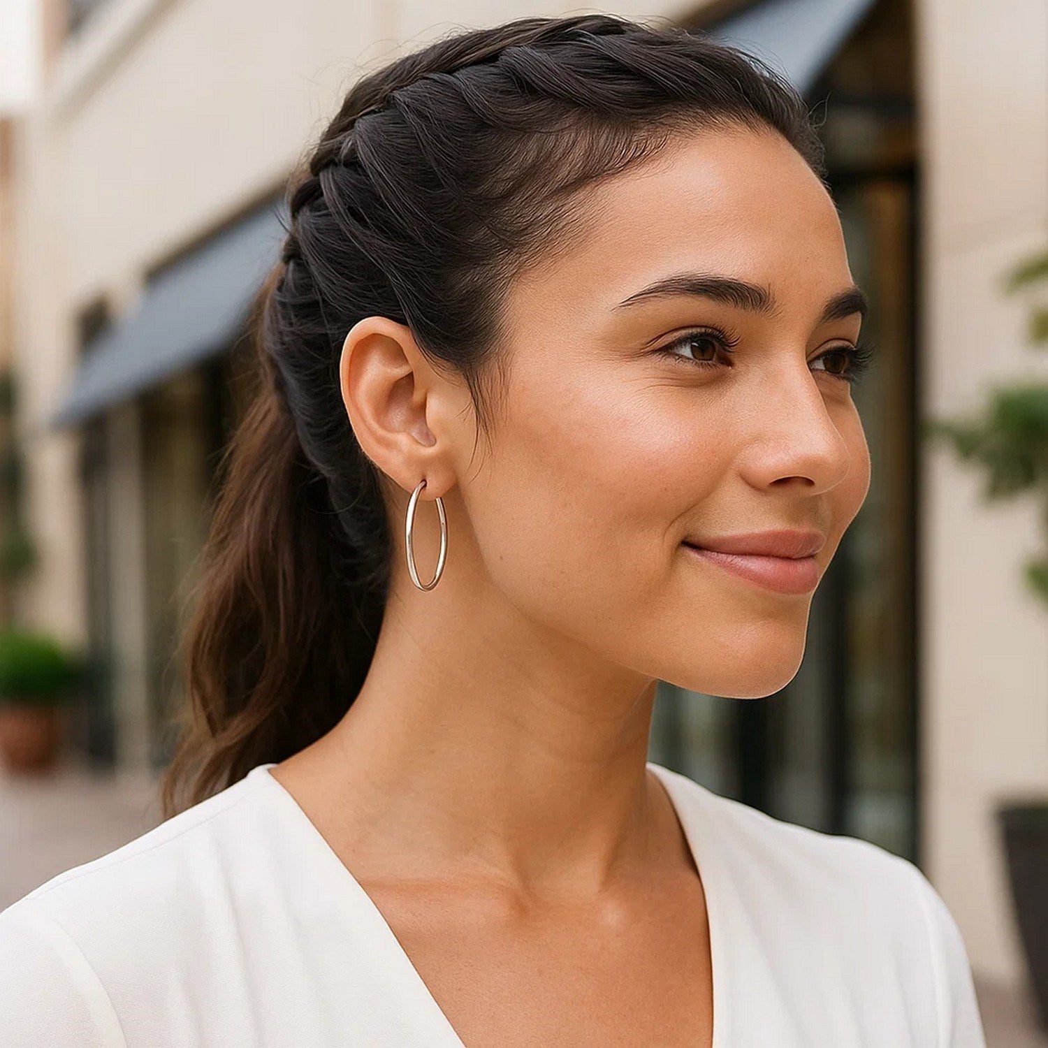 Sterling silver rhodium plated thin and polished hoop earrings on a woman.