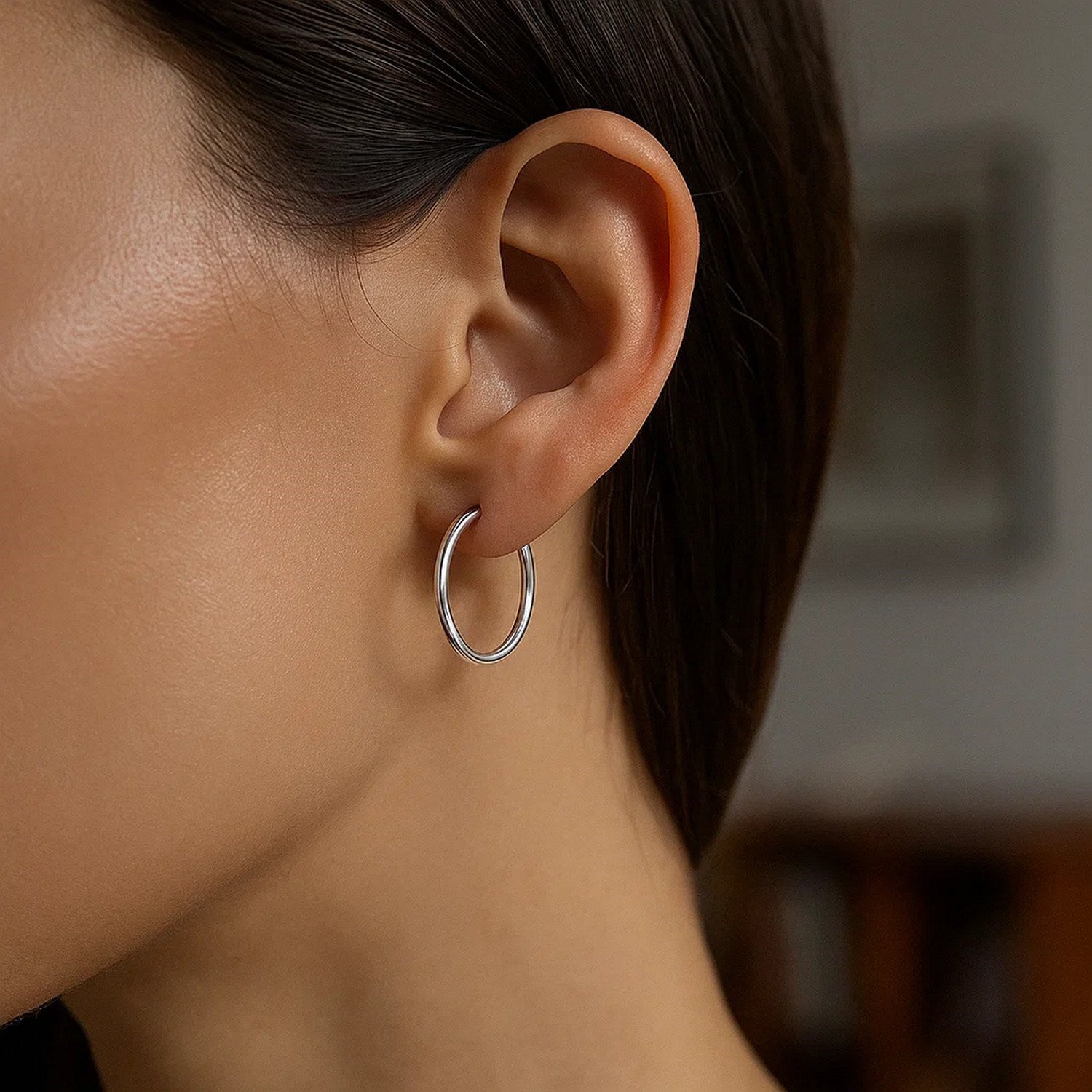 A close-up shows a silver hoop earring on a woman's ear.