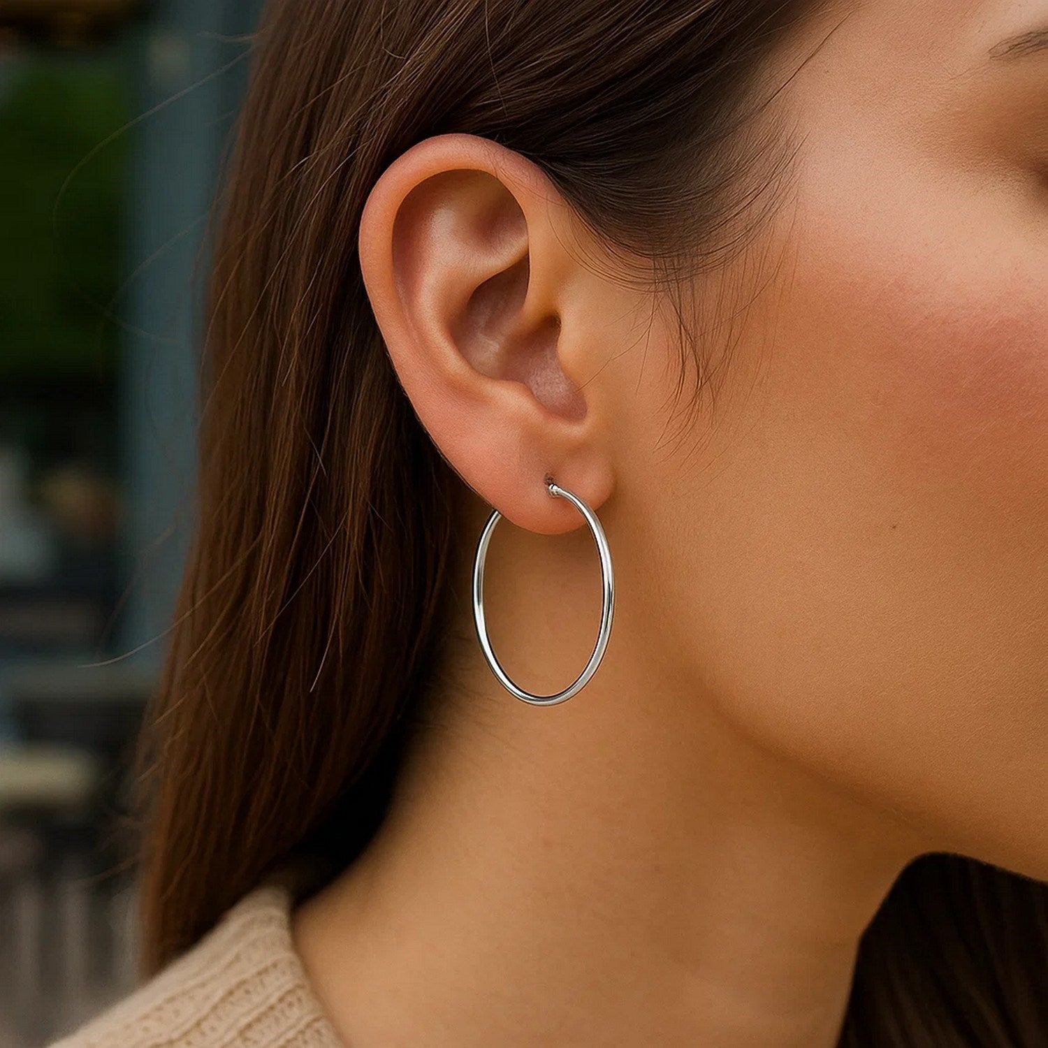 Sterling silver rhodium plated thin large polished hoop earrings on a model.