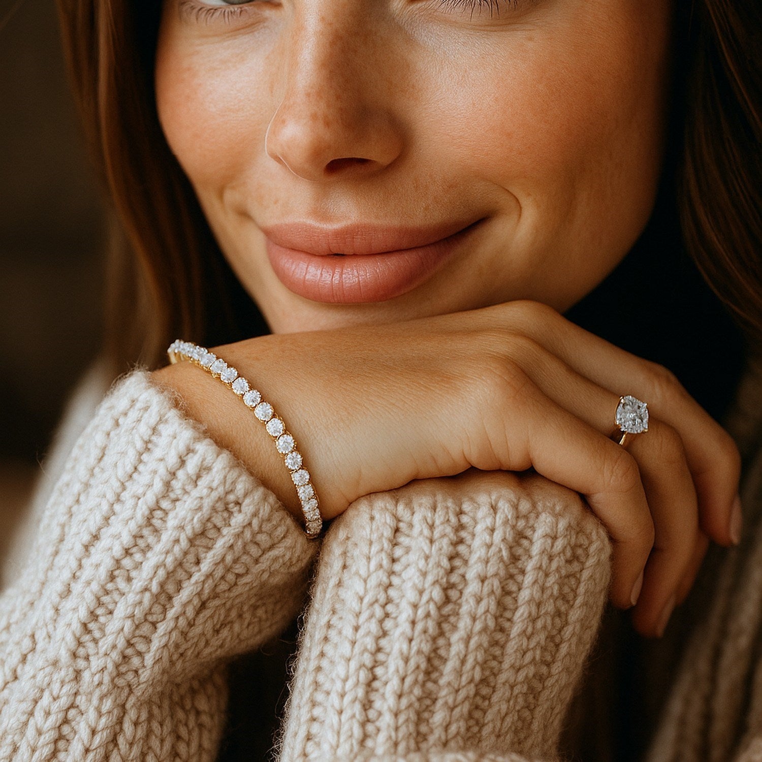 A woman wears a yellow gold lab grown round diamond tennis bracelet and a ring.