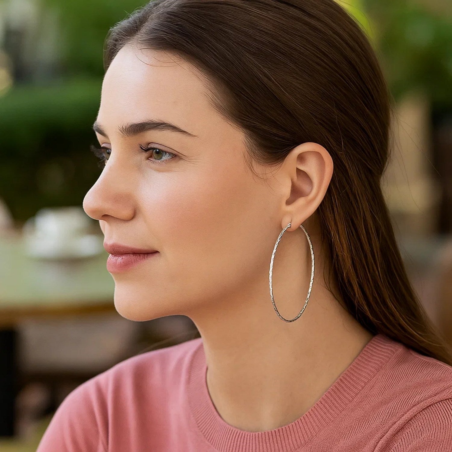 Sterling silver large textured round hoop earrings on a woman.
