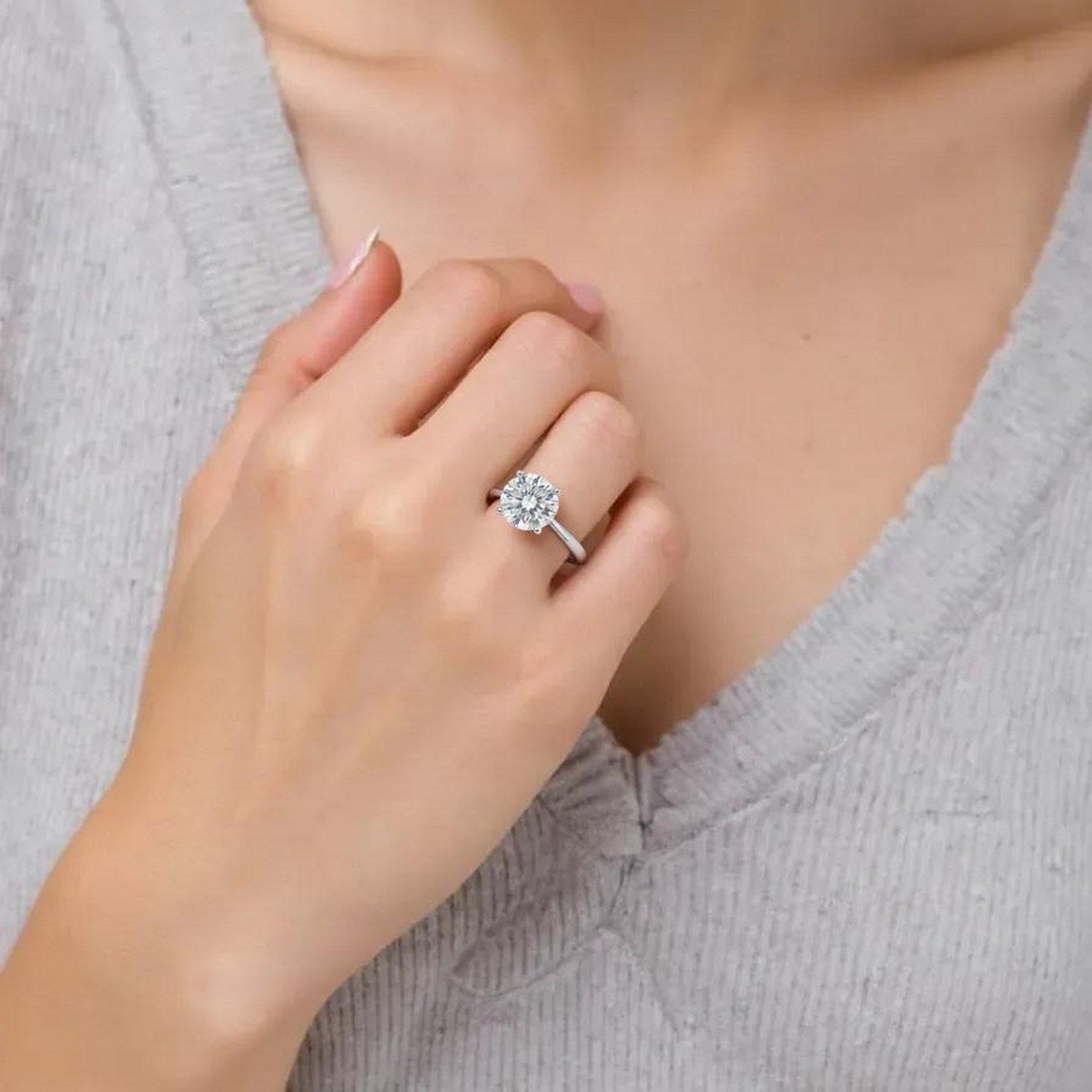 A woman wears a 1 1/2 carat round lab grown diamond ring in 10K white gold.