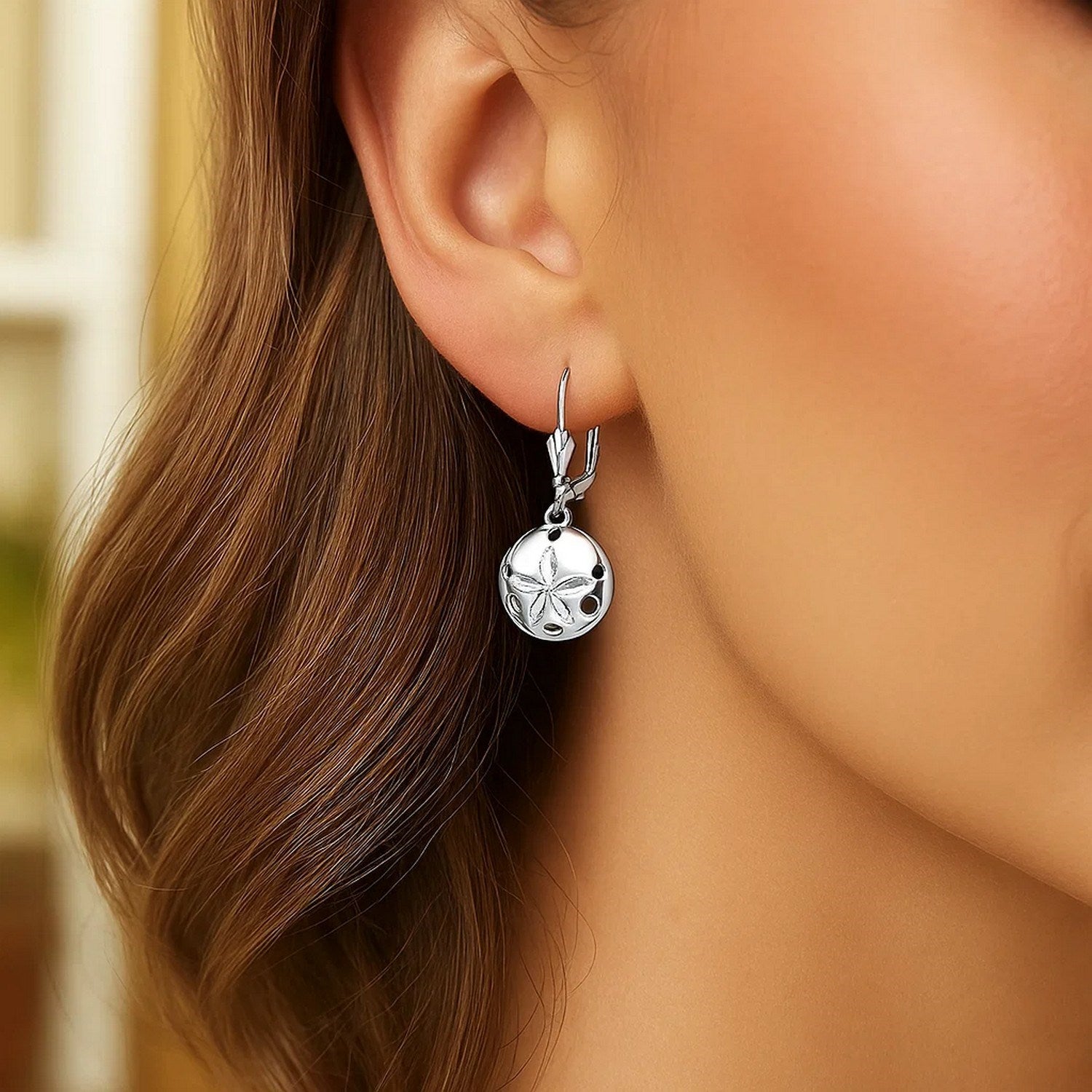 Sterling silver polished sand dollar dangle earrings with lever back clasps.