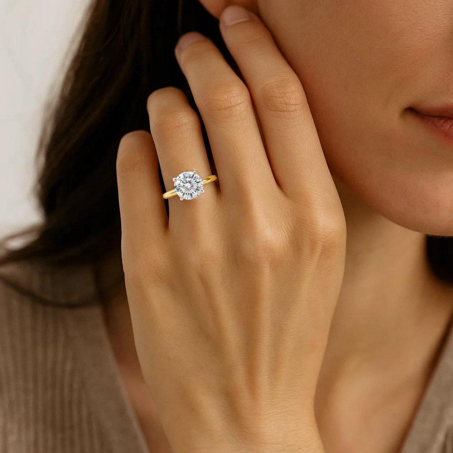 A woman wears a 3 carat round lab grown diamond solitaire ring in 10K yellow gold.