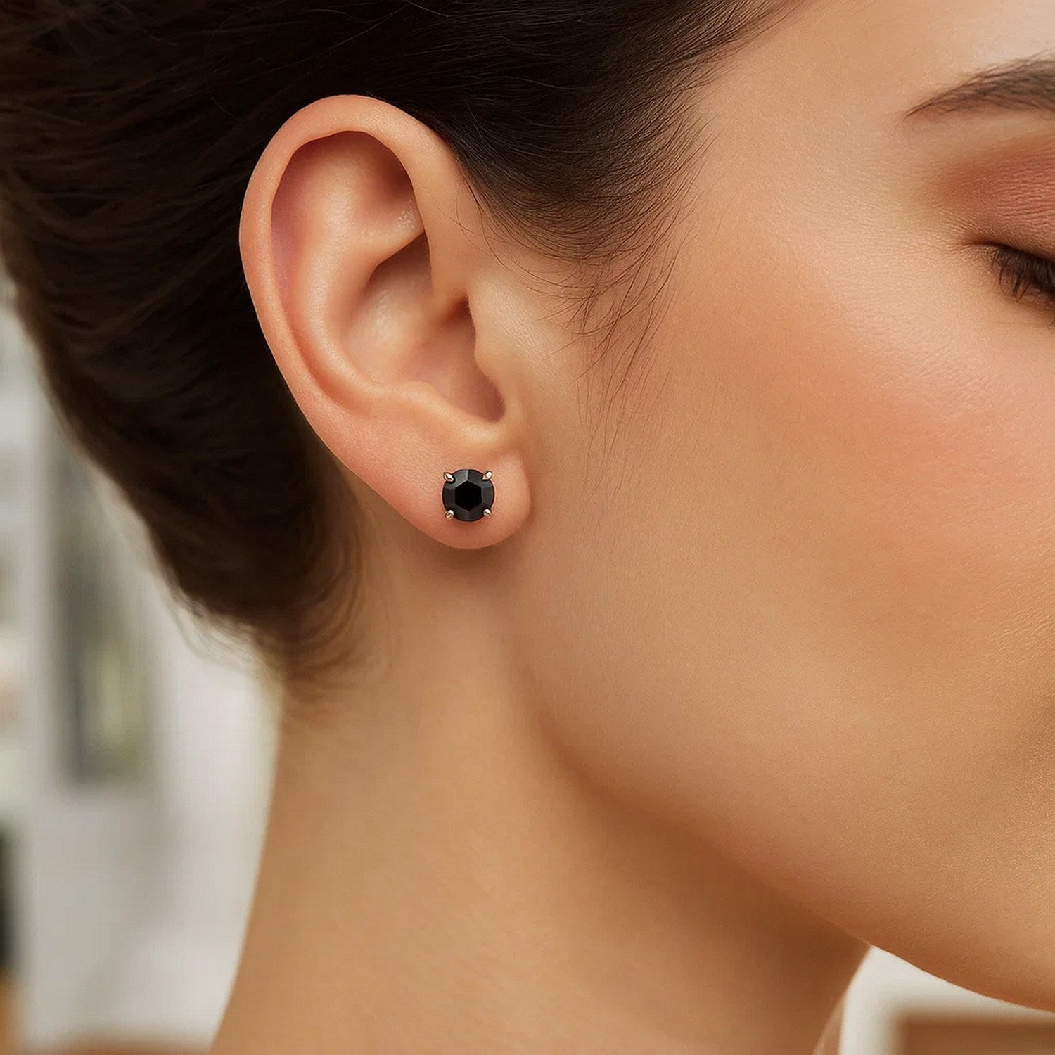 14k white gold stud earrings with black cubic zirconia on a woman's ear.