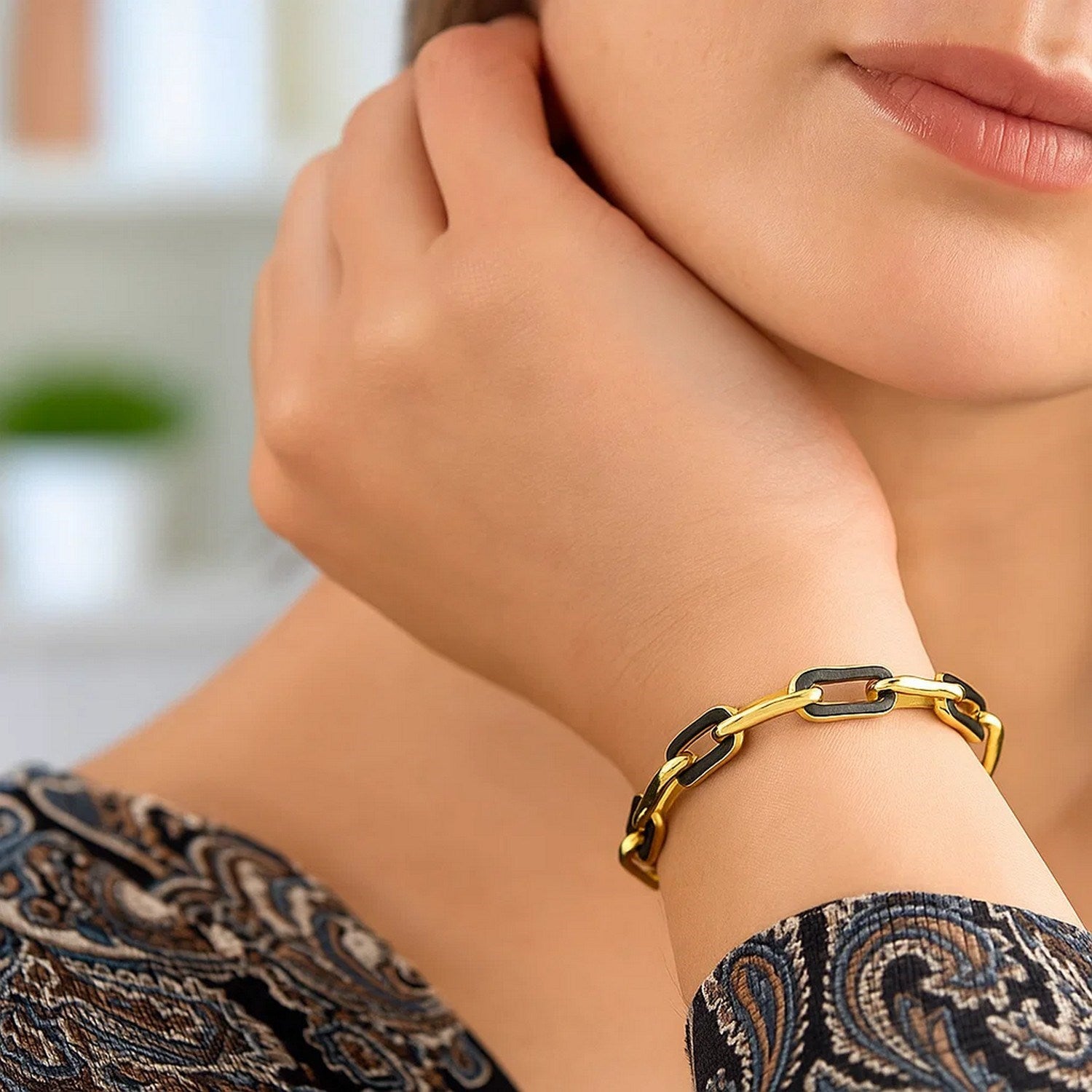 14k yellow gold paperclip link bracelet with black onyx accents on a woman's wrist.