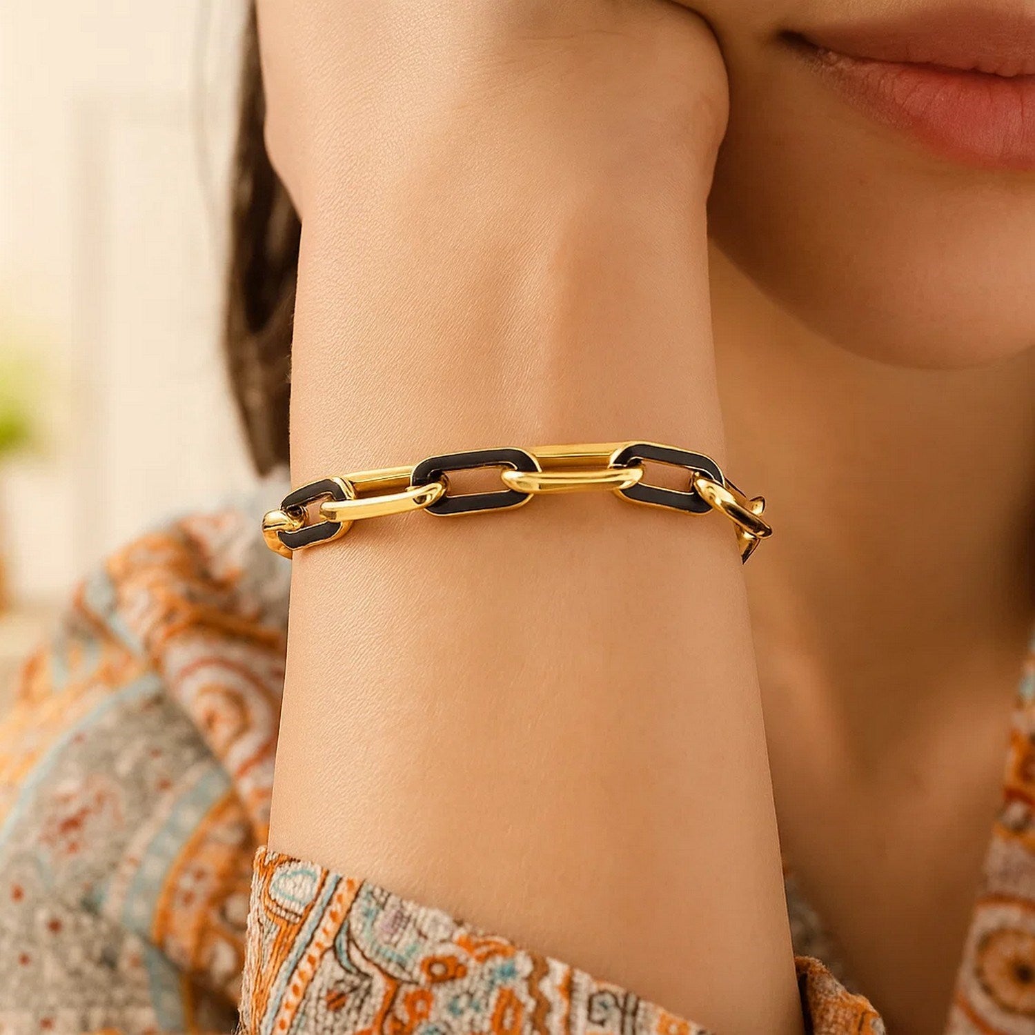 14k yellow gold paperclip link bracelet with black onyx accents on a person's wrist.