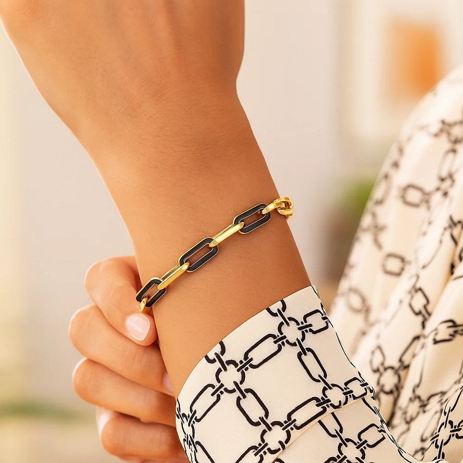 14k yellow gold paperclip link bracelet with black onyx accents on a woman's wrist.