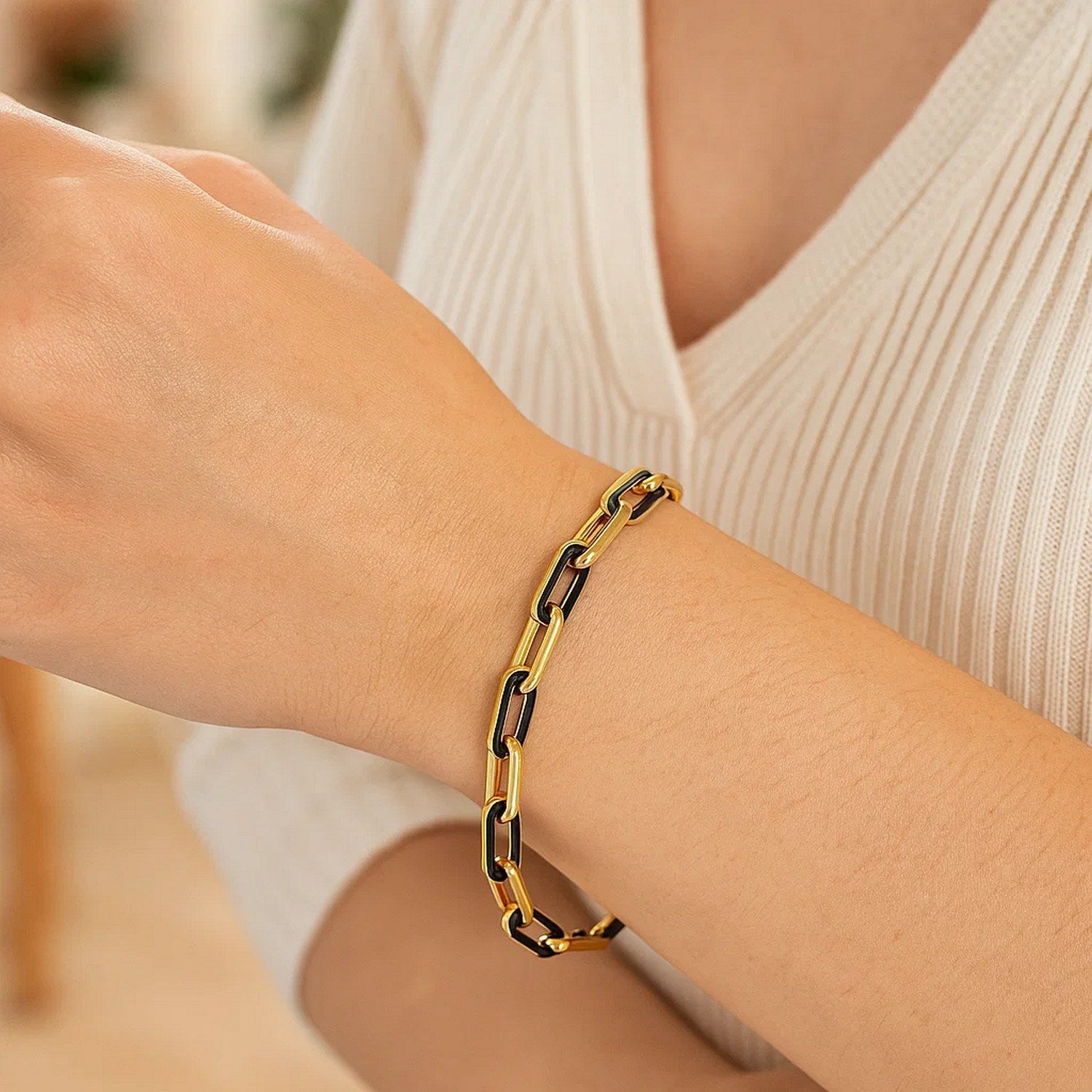 14k yellow gold paperclip link bracelet with black onyx links on a woman's wrist.