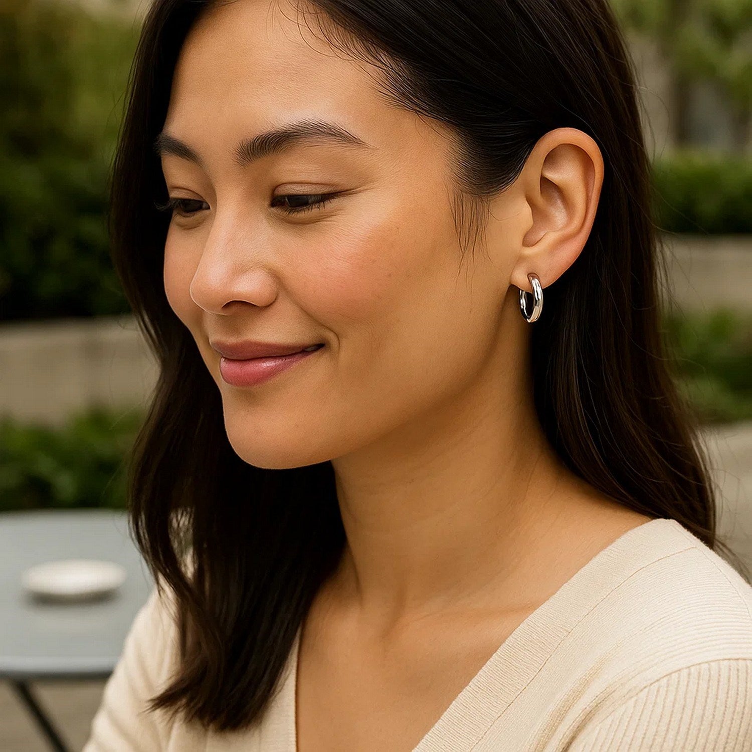 Sterling silver polished hoop earrings with rhodium plating on a woman.