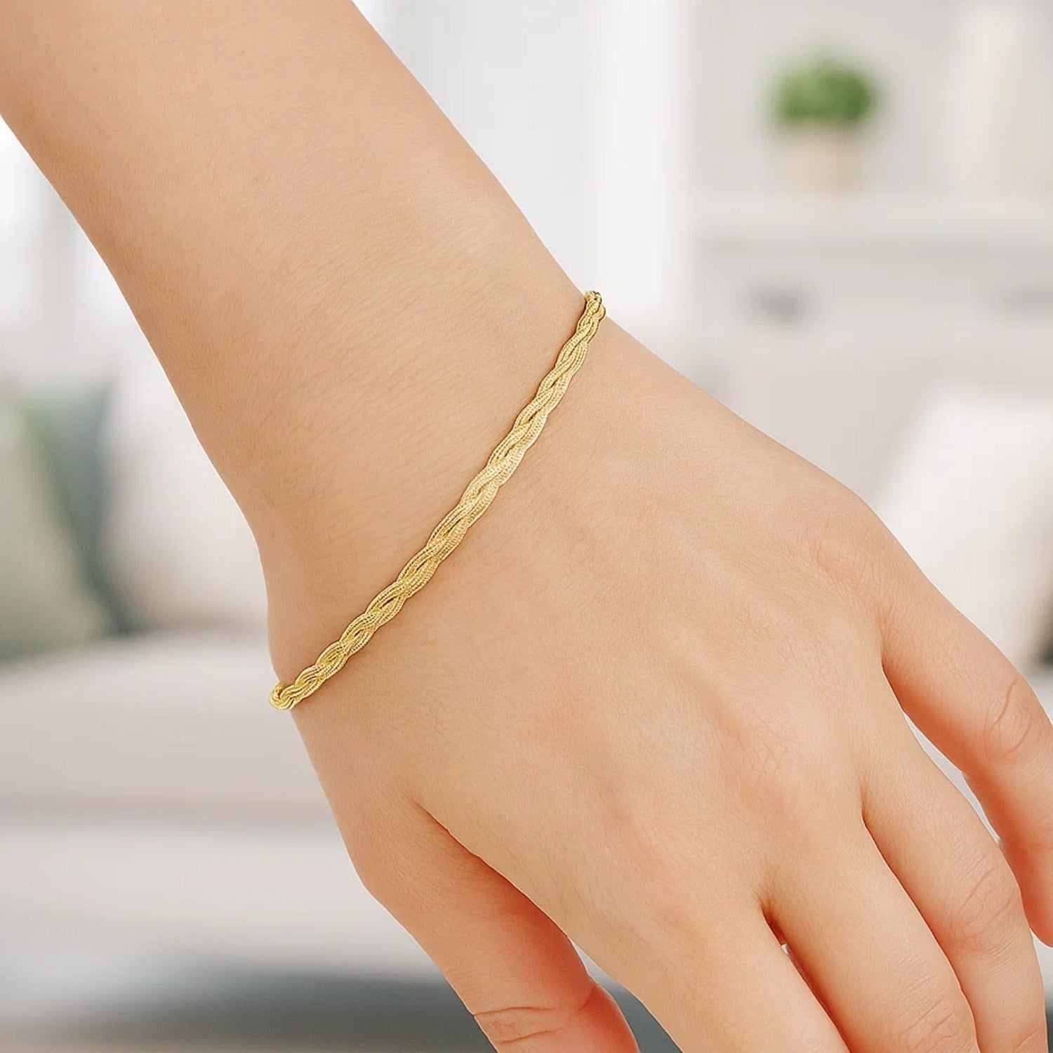 14k yellow gold braided herringbone bracelet on a person's wrist.