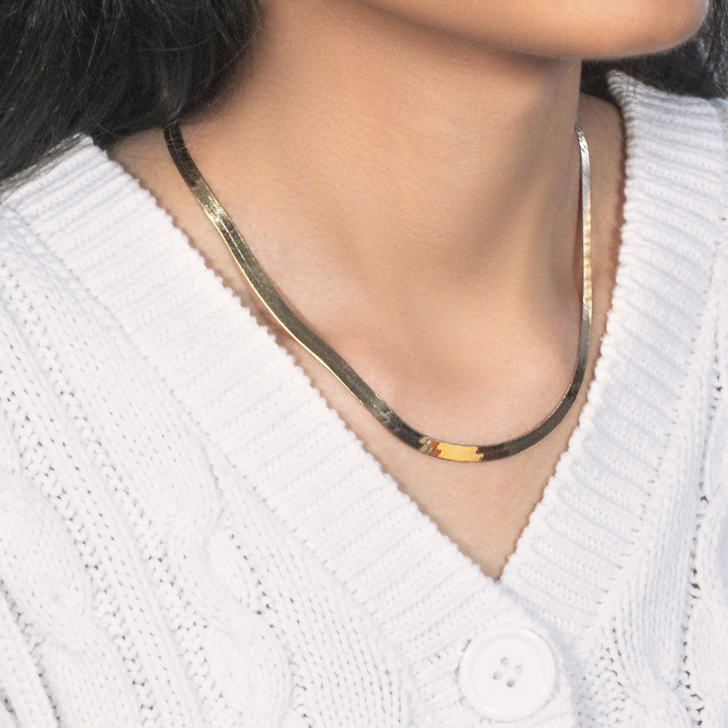 A 10k yellow gold herringbone chain, 5.00 mm wide, worn around a person's neck.