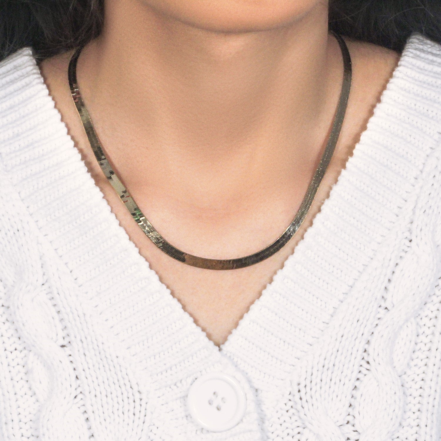 A 10k yellow gold herringbone chain is worn around a person's neck.