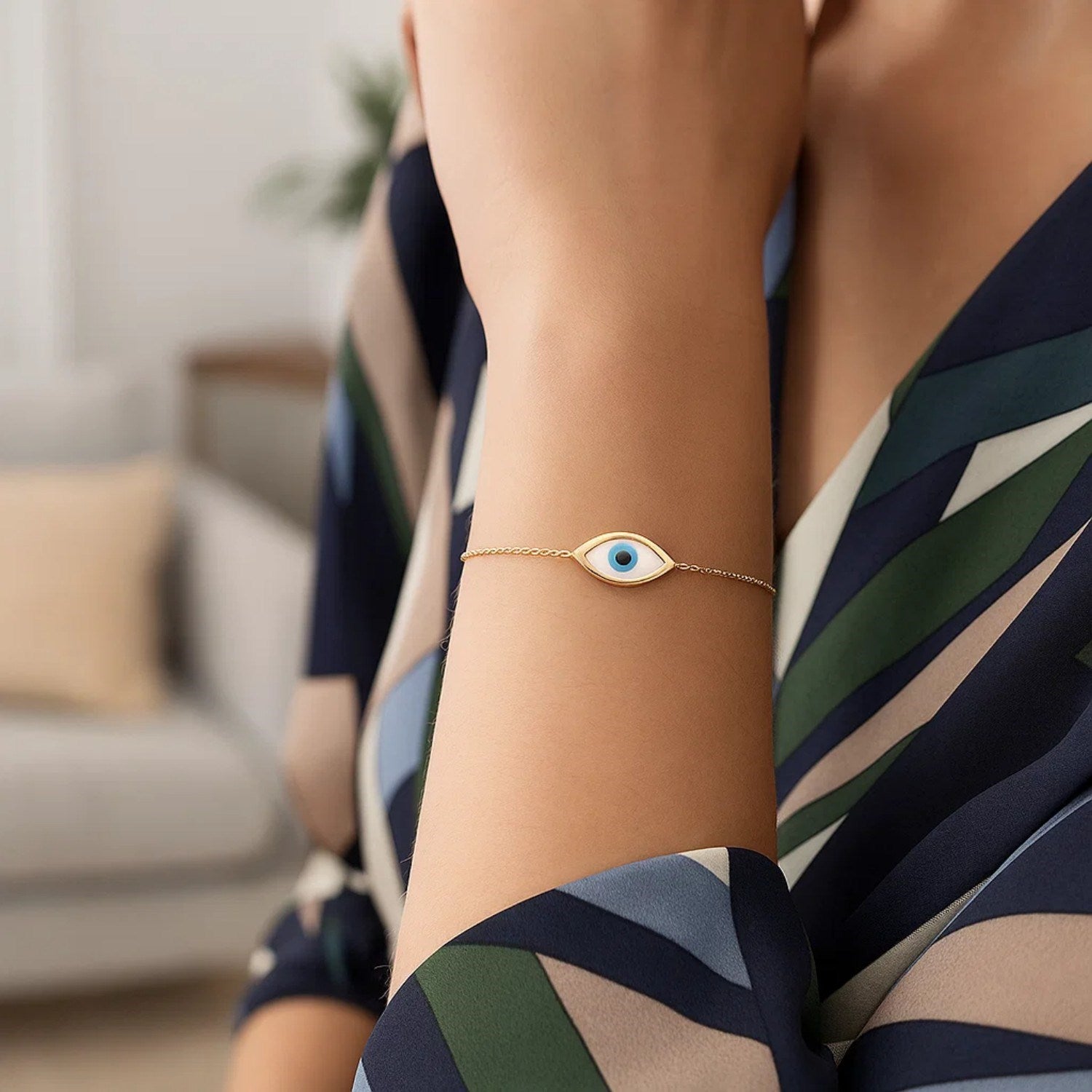 A 14k yellow gold evil eye bracelet with a mother-of-pearl center on a woman's arm.