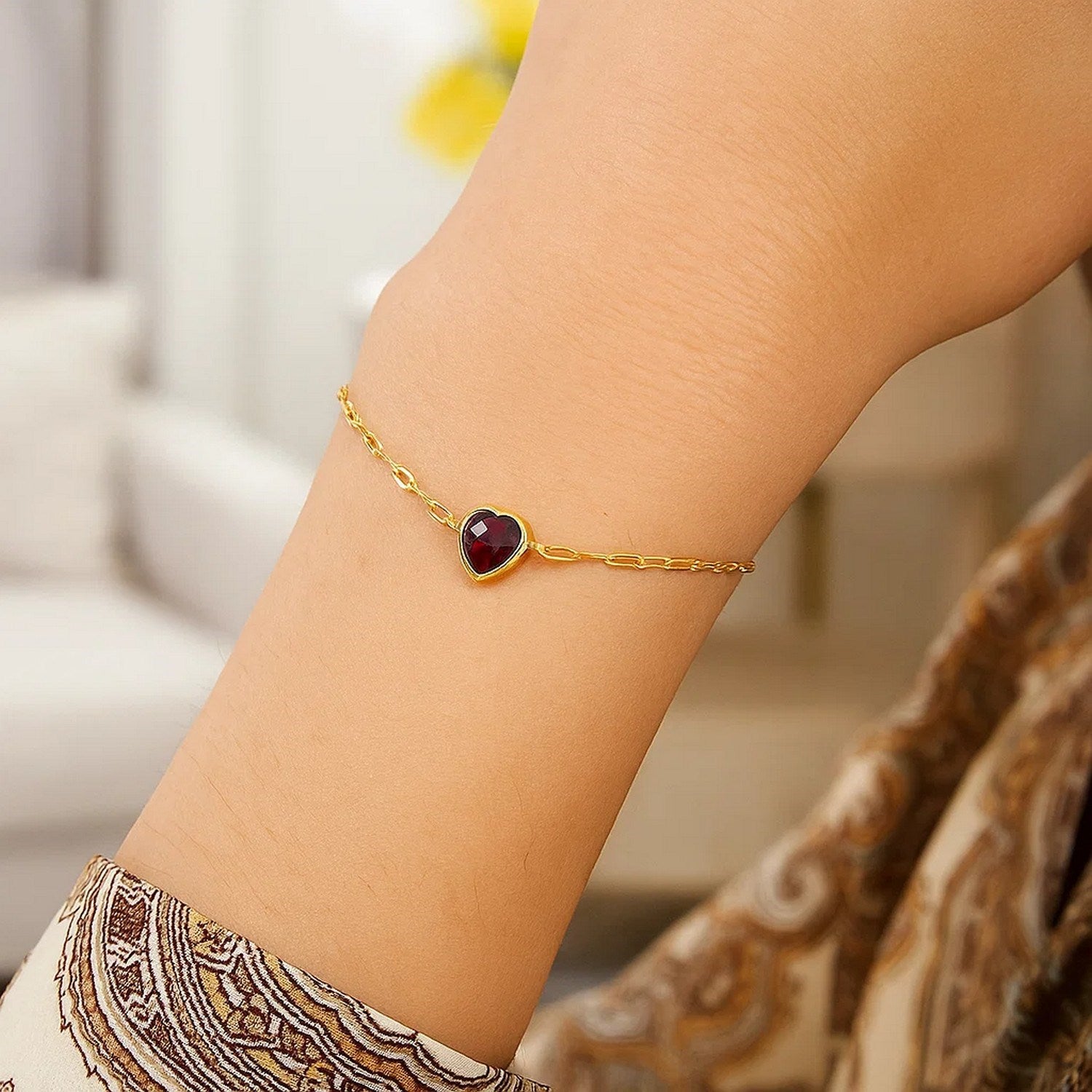 14K yellow gold link bracelet with a bezel-set heart-shaped garnet.