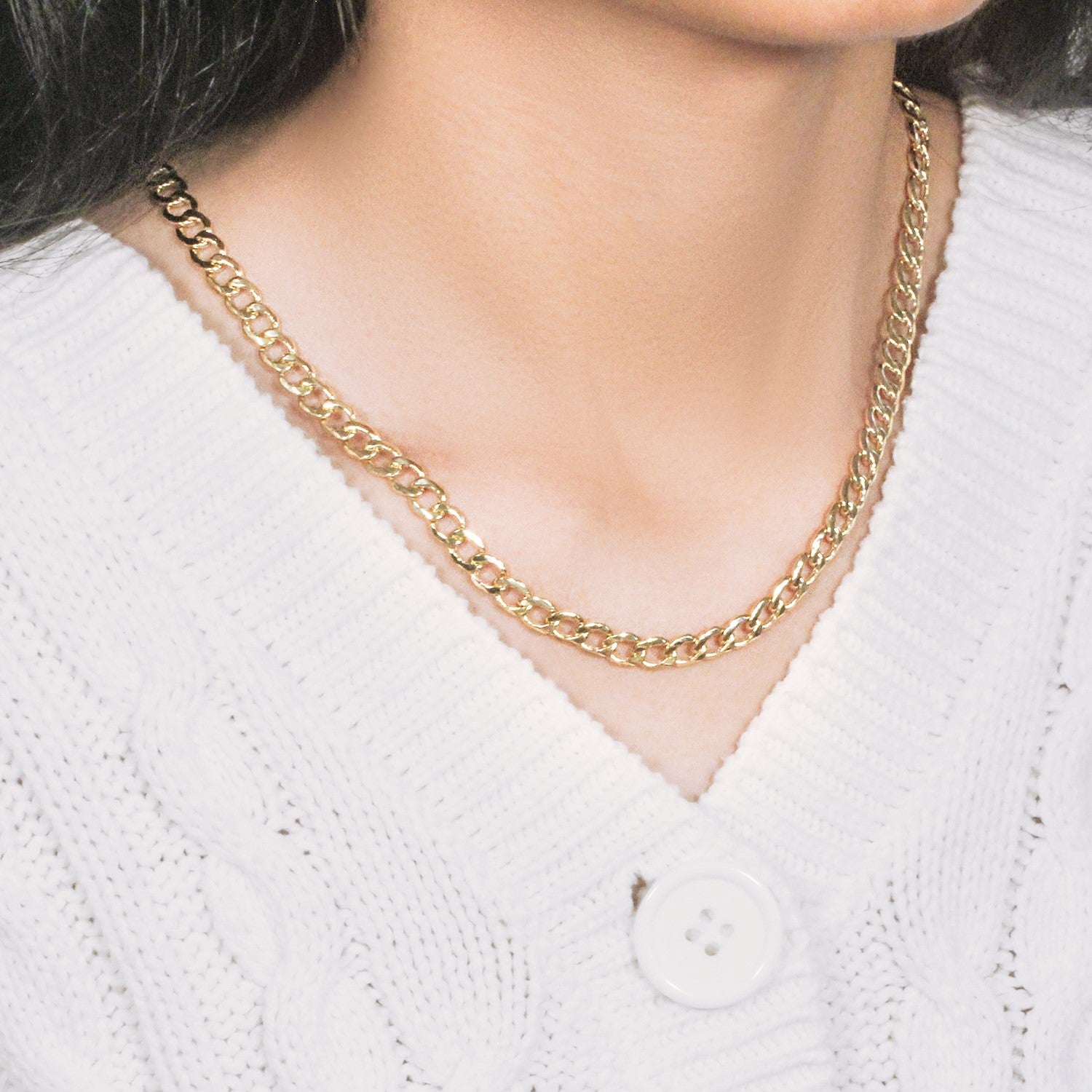 10k yellow gold curb chain with a lobster clasp on a person wearing a white sweater.