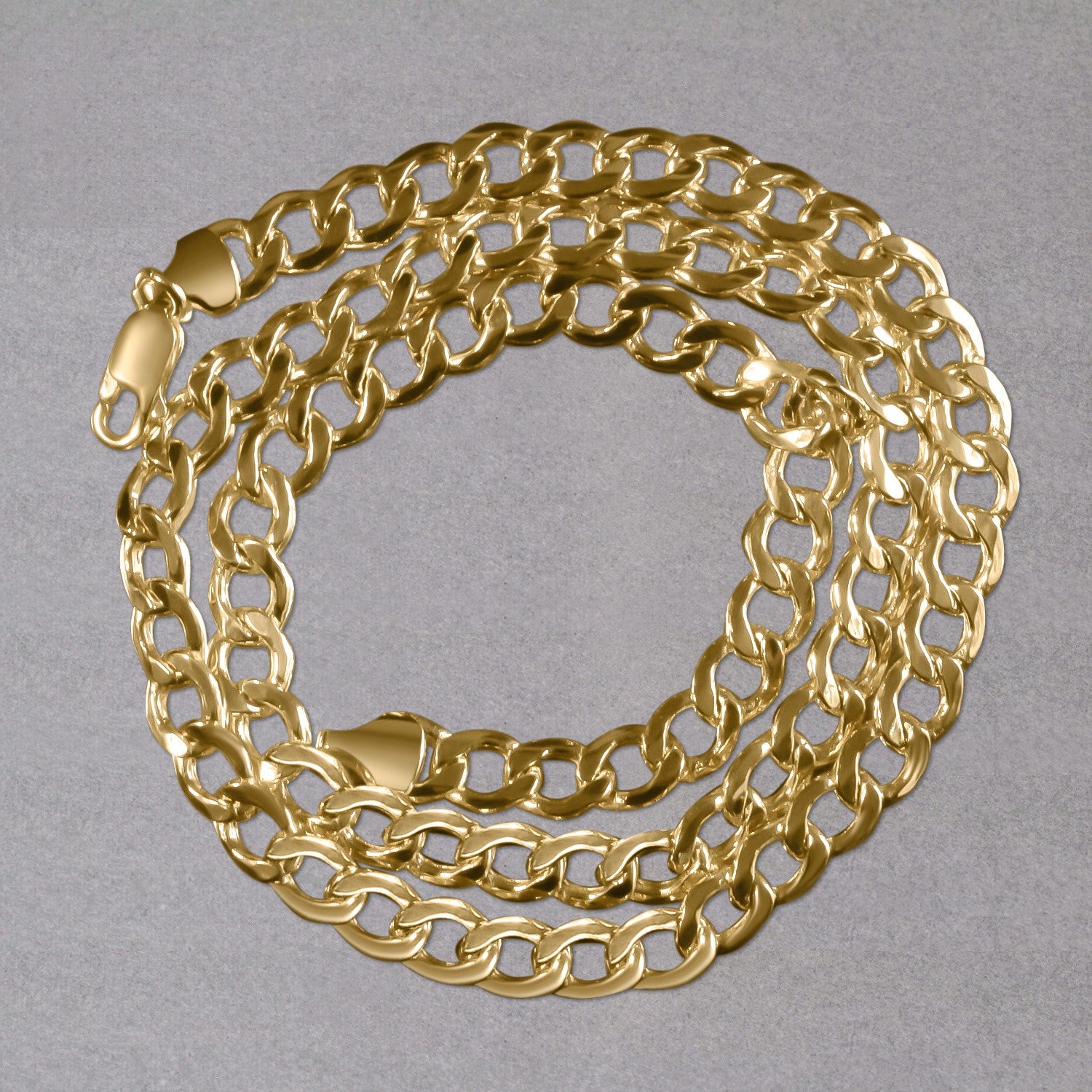 A 10k yellow gold curb chain with a lobster clasp is coiled on a gray surface.