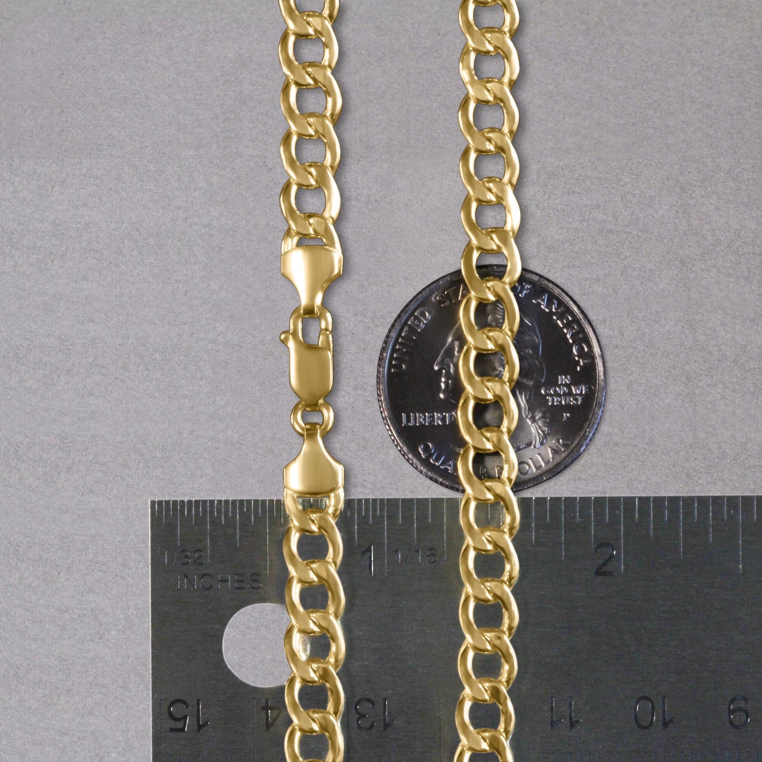 A 10k yellow gold curb chain with a lobster clasp, measured against a ruler and a quarter.