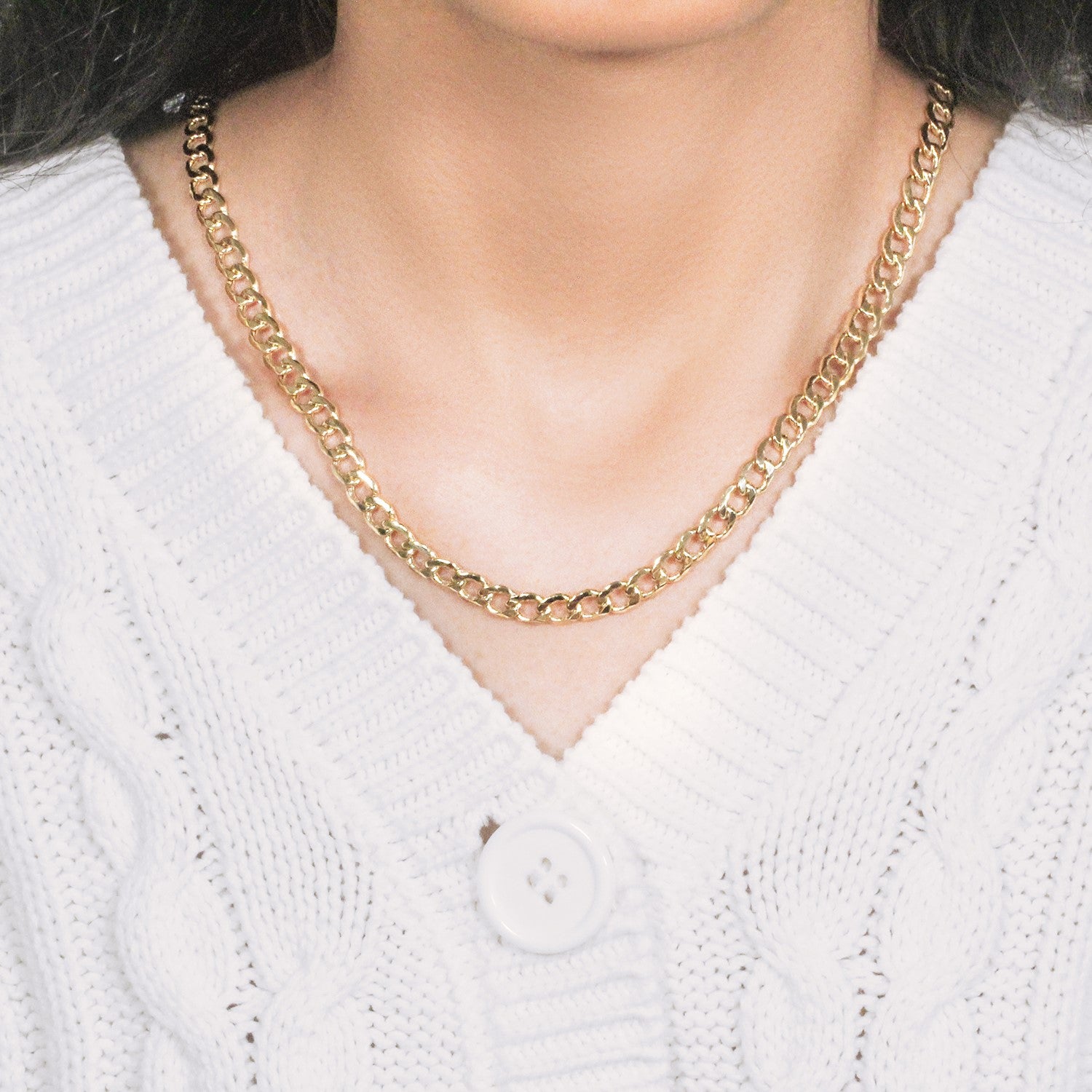 10k yellow gold curb chain on a person wearing a white cable-knit cardigan.