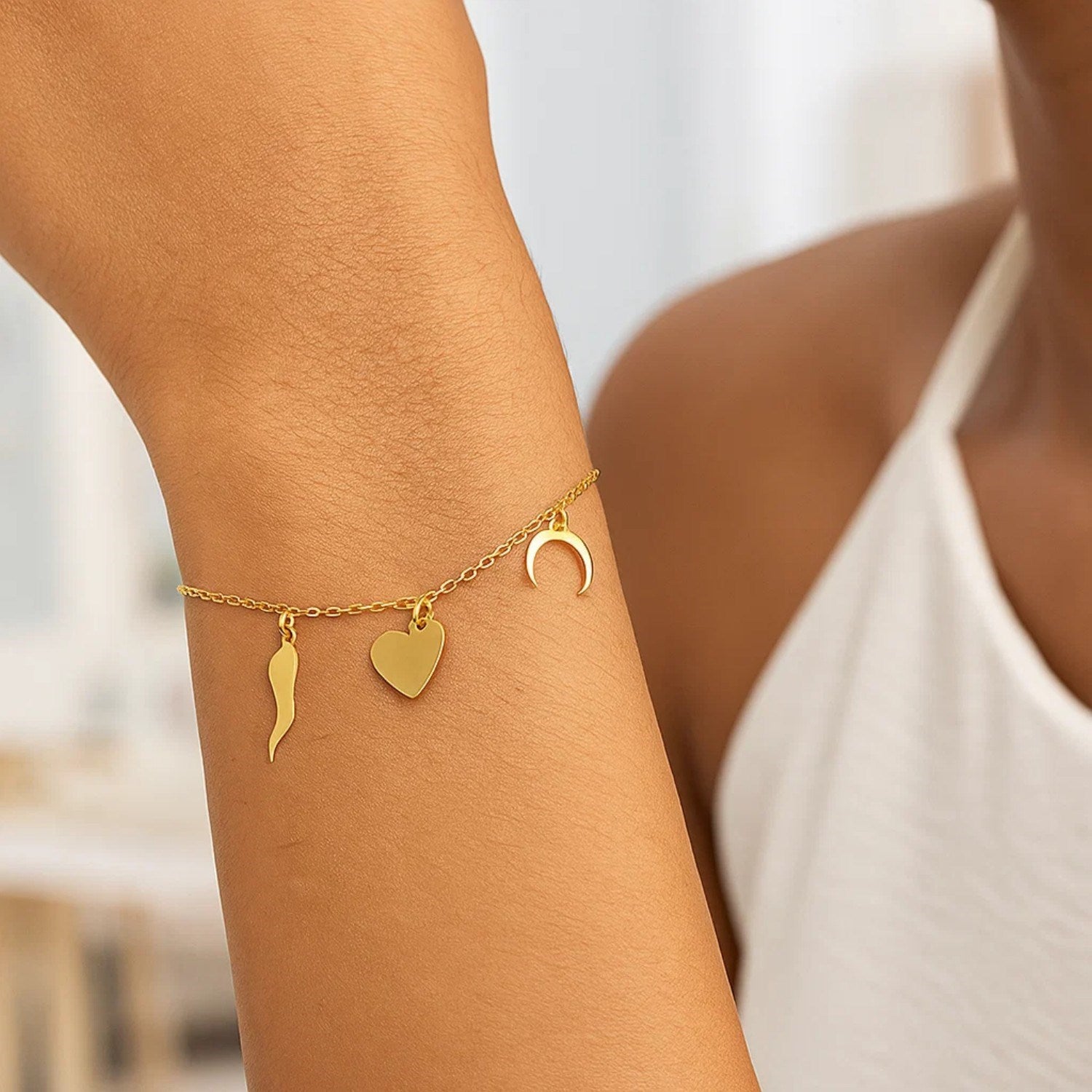 14k yellow gold bracelet with a horn, heart, and crescent moon charm.