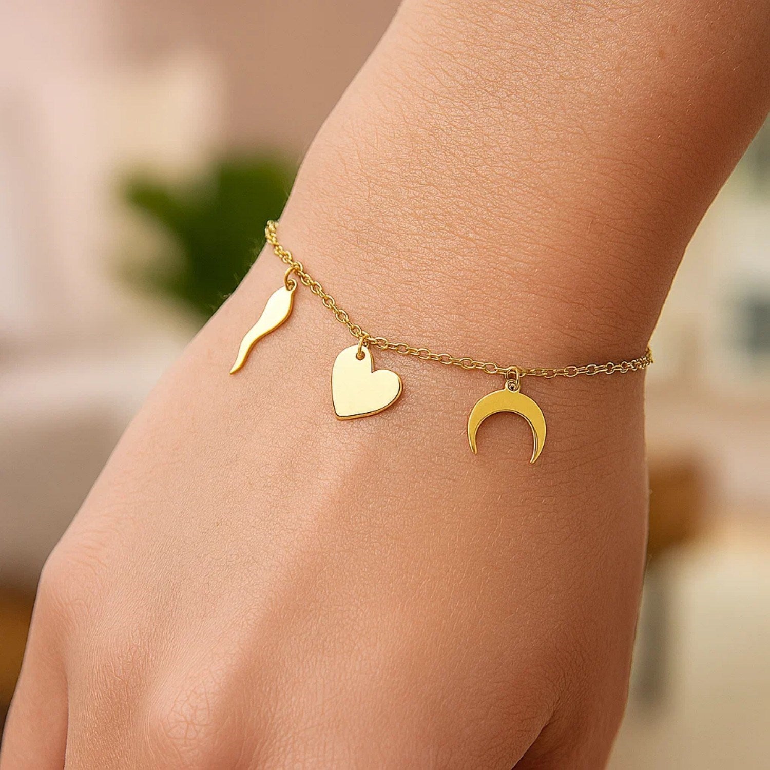 14k yellow gold bracelet with a horn, heart, and crescent moon charm.