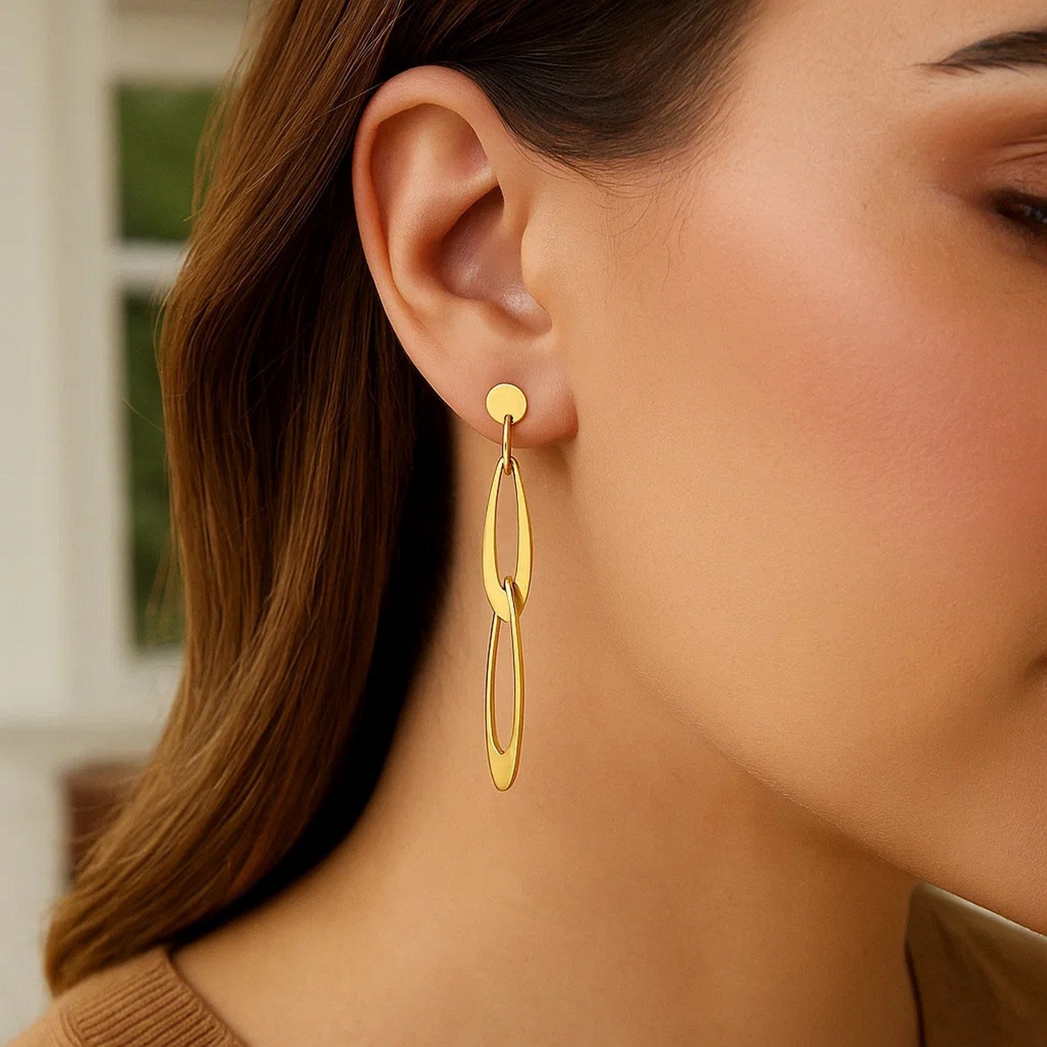 14k yellow gold Italian oval link earrings on a woman's ear.