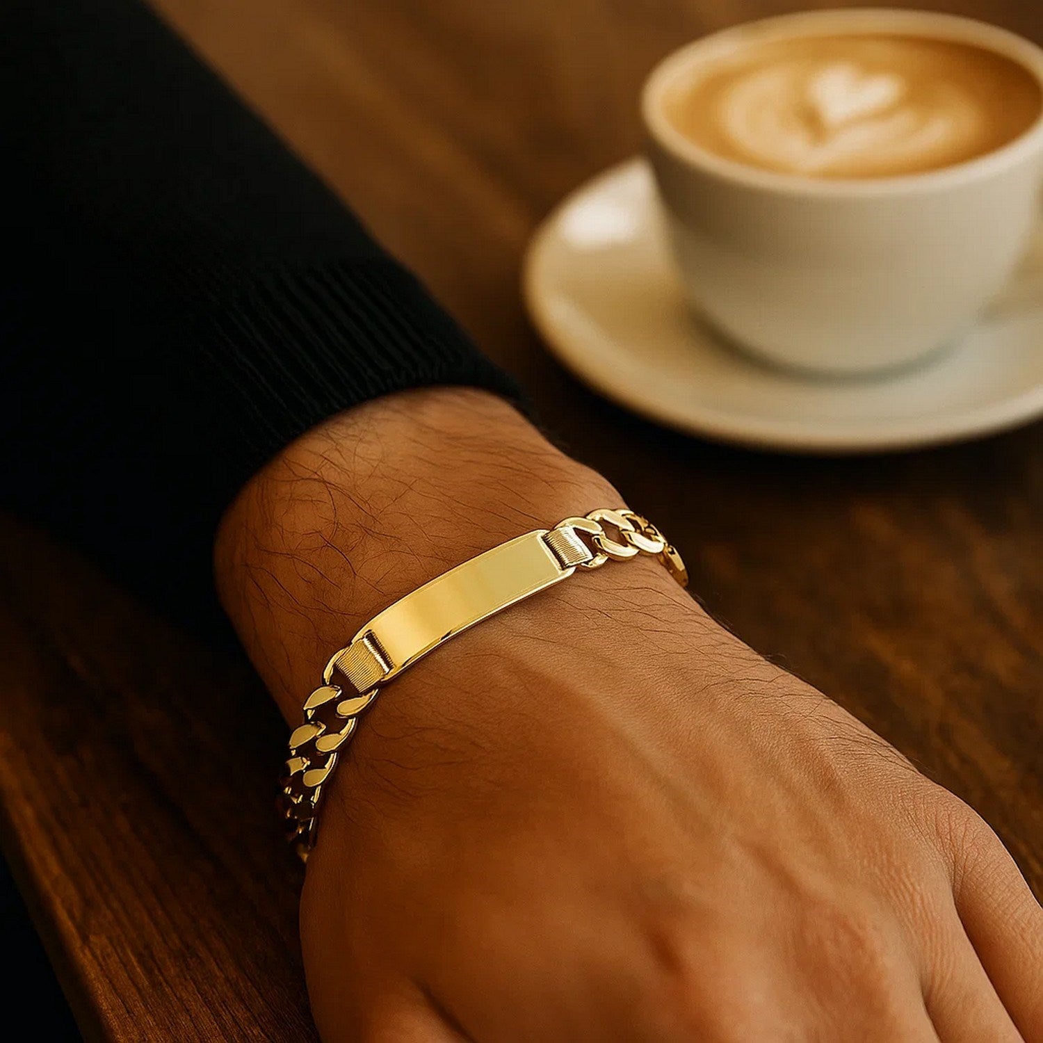 14k yellow gold curb ID bracelet on a person's wrist, with a coffee cup in the background.