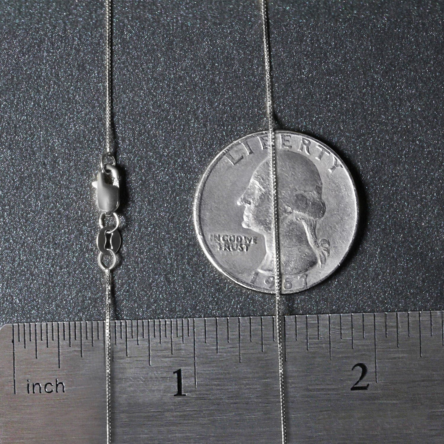 A 10k white gold classic box chain with a lobster clasp, measured against a ruler and coin.