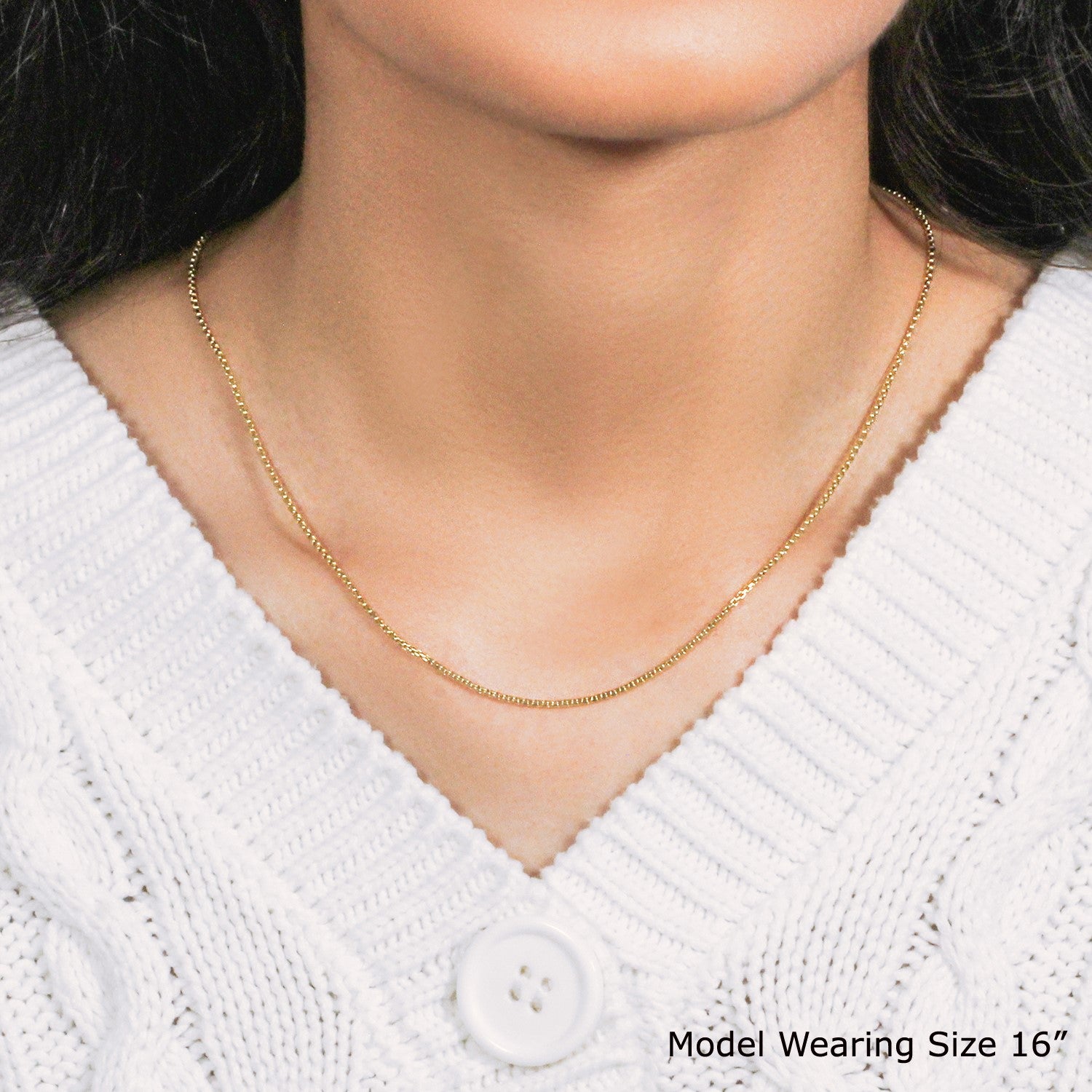 A 14k yellow gold round box chain, 1.3mm wide, worn by a model.