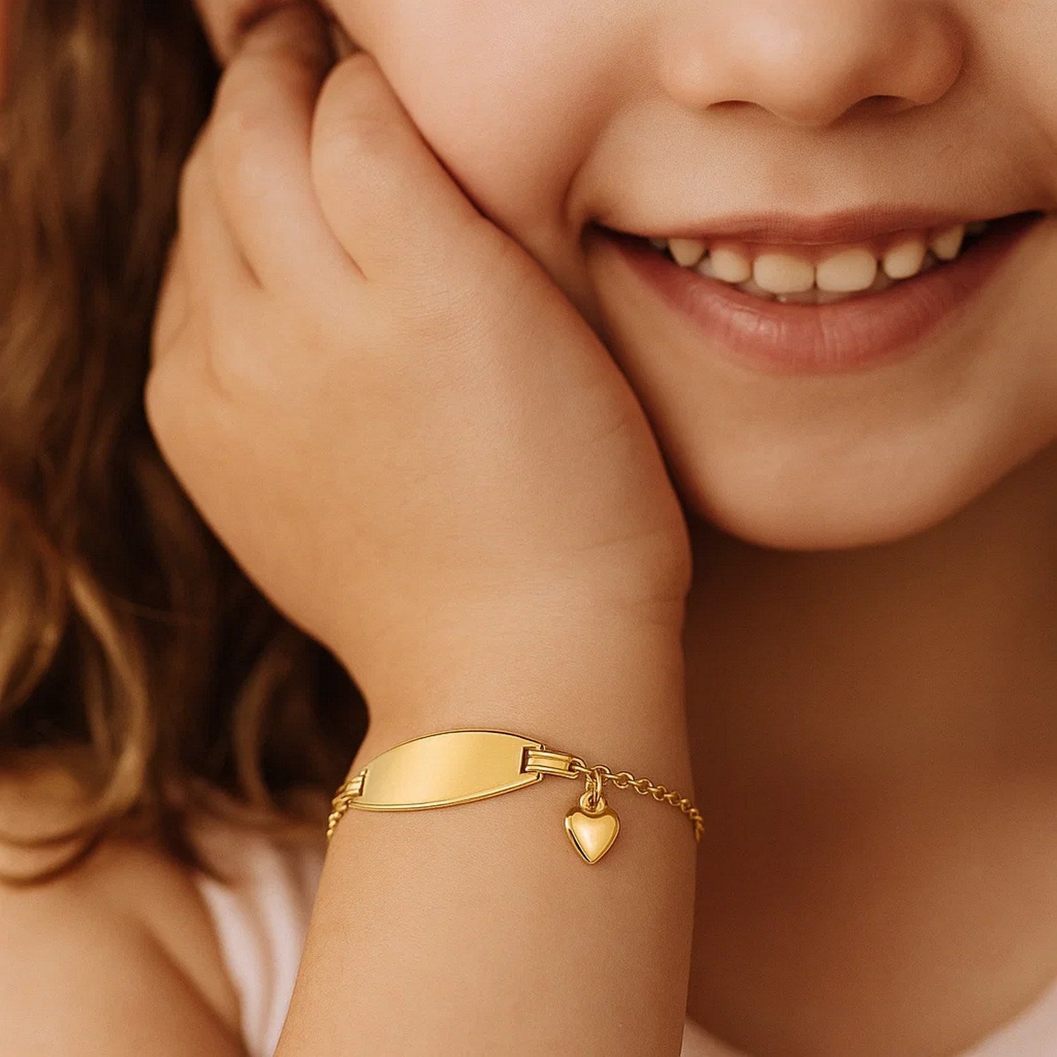 14k yellow gold children's ID bracelet with a heart charm on a child's wrist.