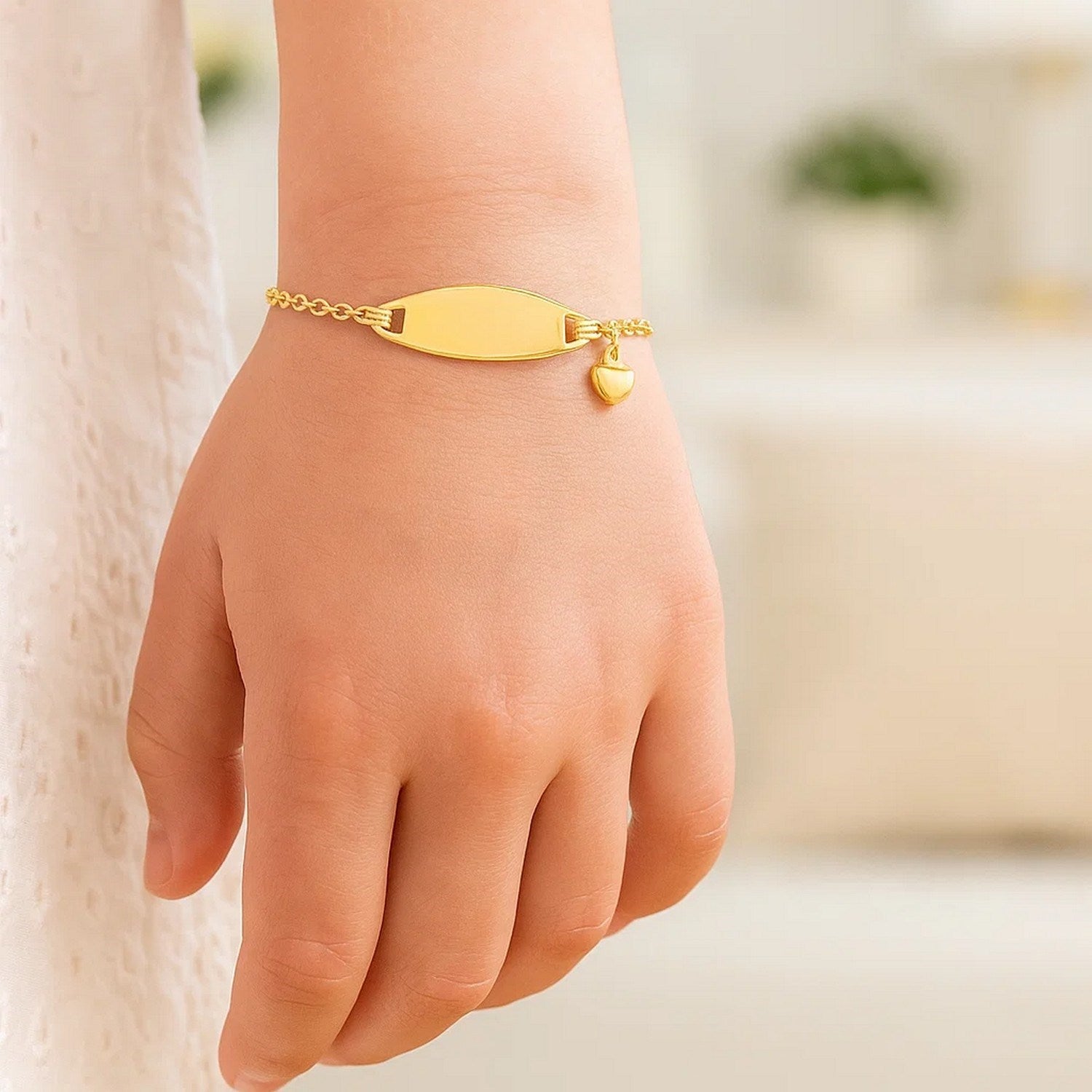 14k yellow gold cable chain ID bracelet with a heart charm on a child's wrist.