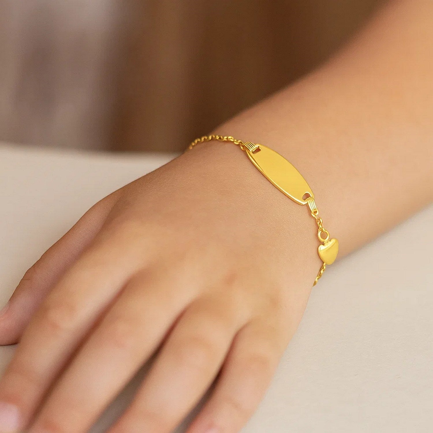 14k yellow gold children's ID bracelet with an oval plate and heart accent.