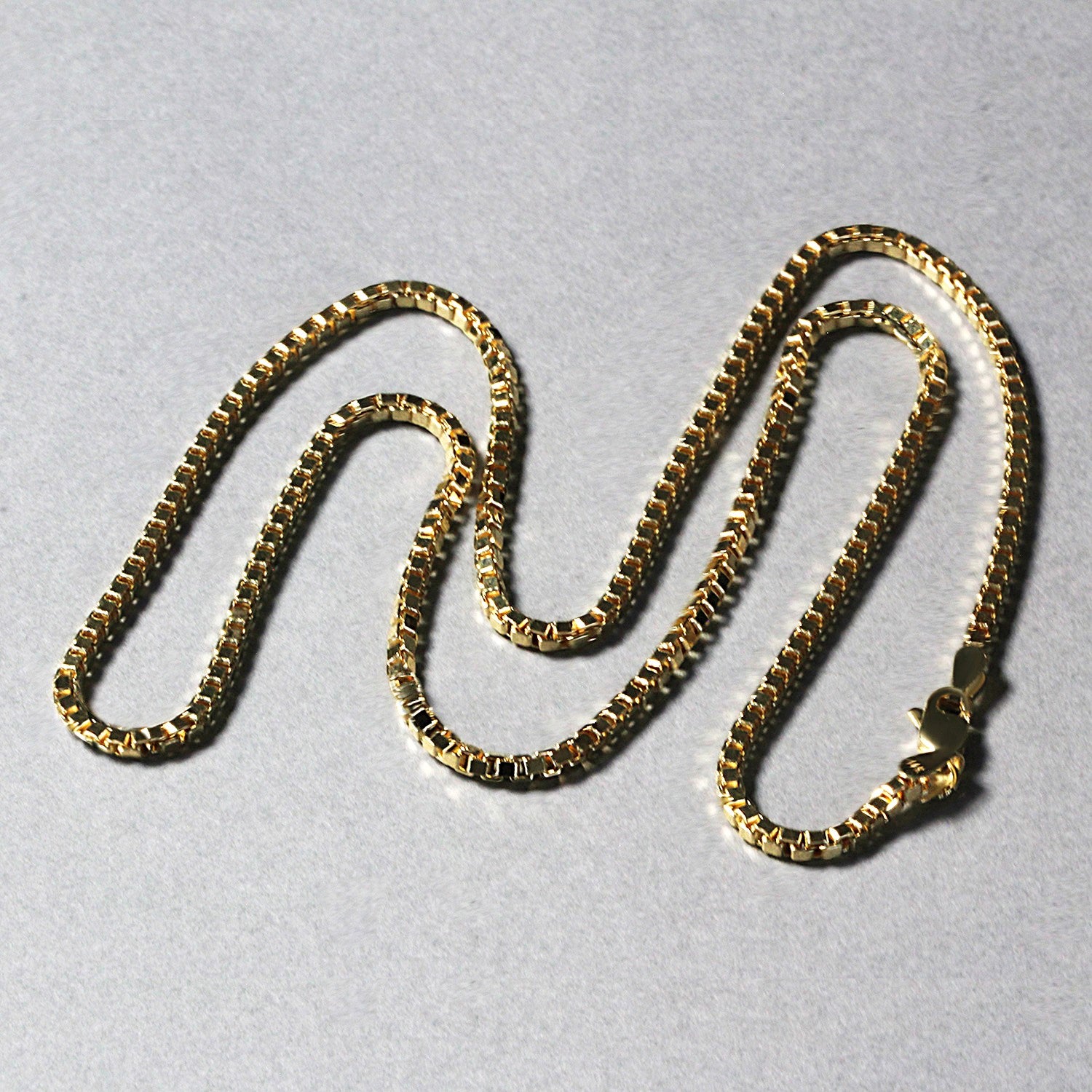A semi-solid 14k yellow gold box chain with a lobster clasp.