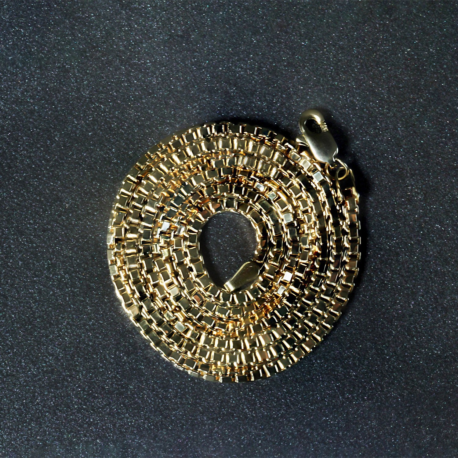 A 14k yellow gold semi-solid box chain, 2.10 mm wide, coiled on a dark background.