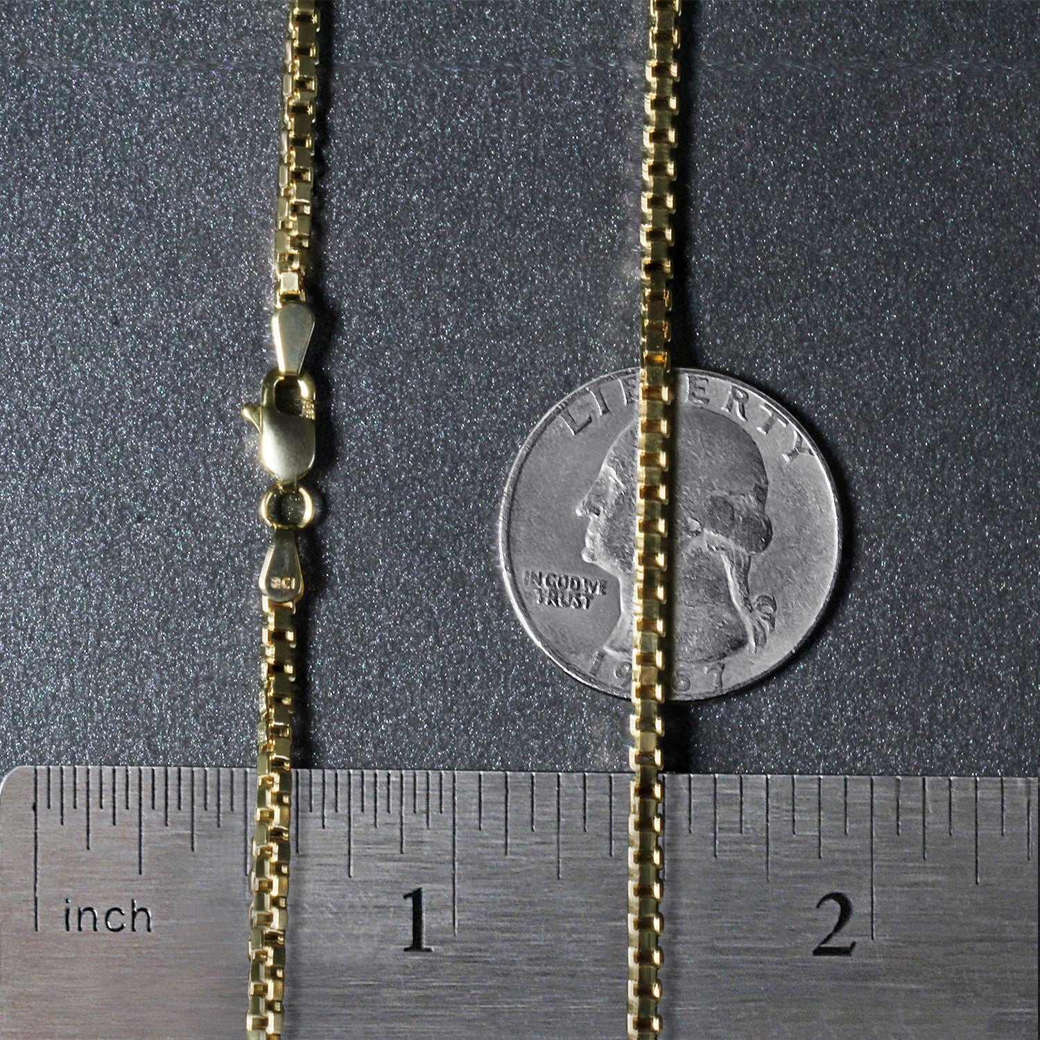 A 14k yellow gold semi-solid box chain with a lobster clasp, measured against a ruler and coin.