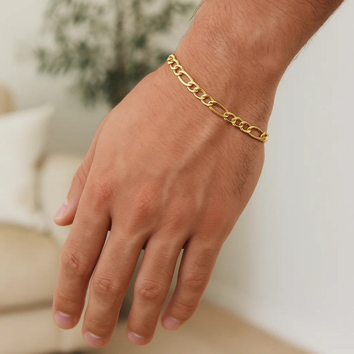 A 10k yellow gold Figaro link bracelet on a person's wrist.