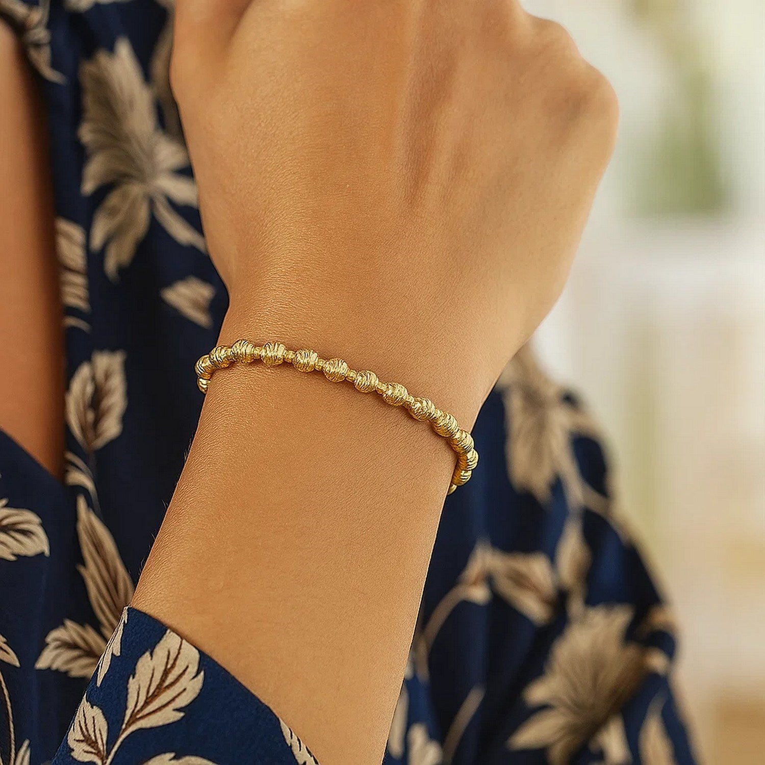 14K yellow gold disco diamond cut bead bracelet on a person's wrist.