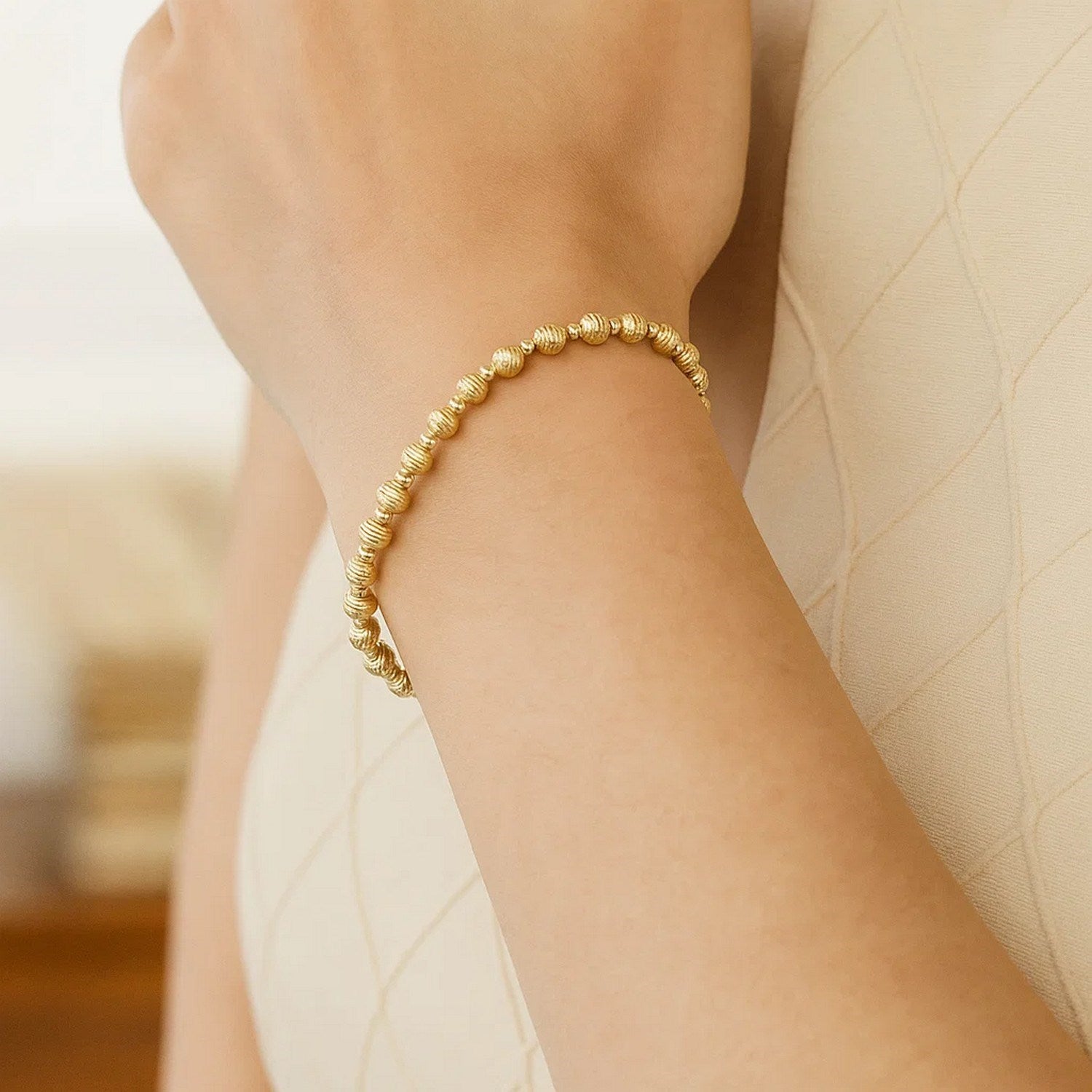 14K yellow gold disco diamond-cut bead bracelet on a person's wrist.