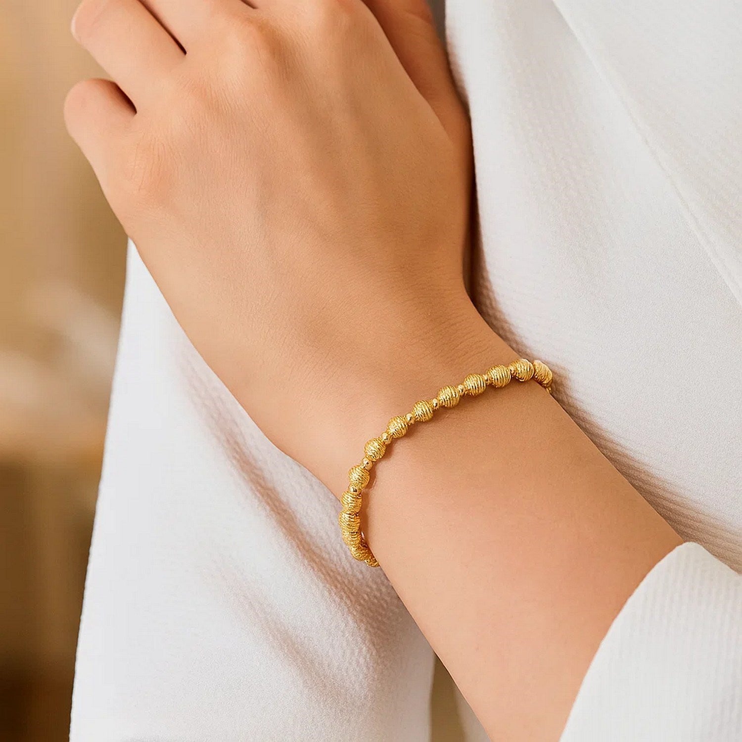14K yellow gold disco diamond-cut bead bracelet on a person's wrist.