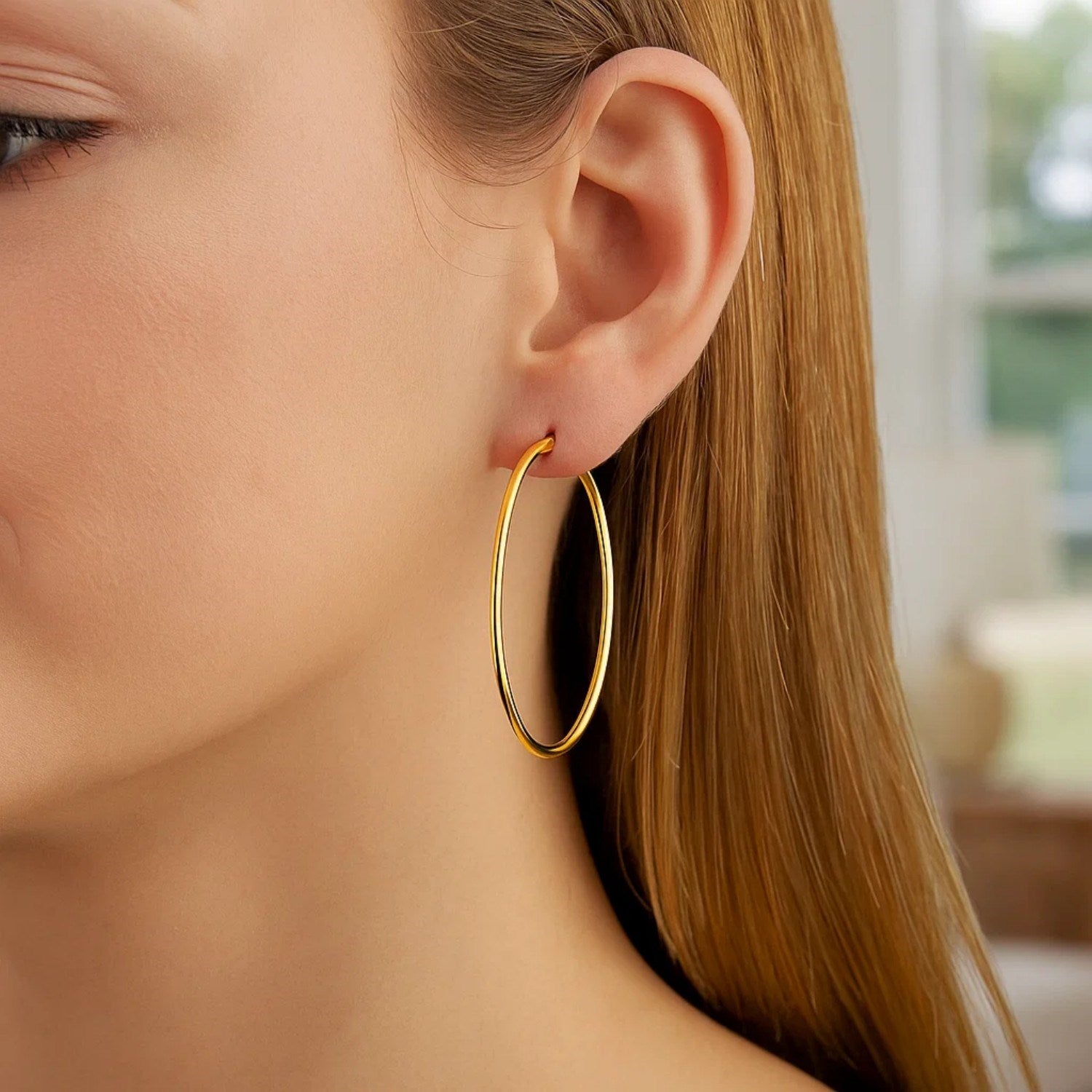 10k yellow gold polished hoop earrings on a woman's ear.