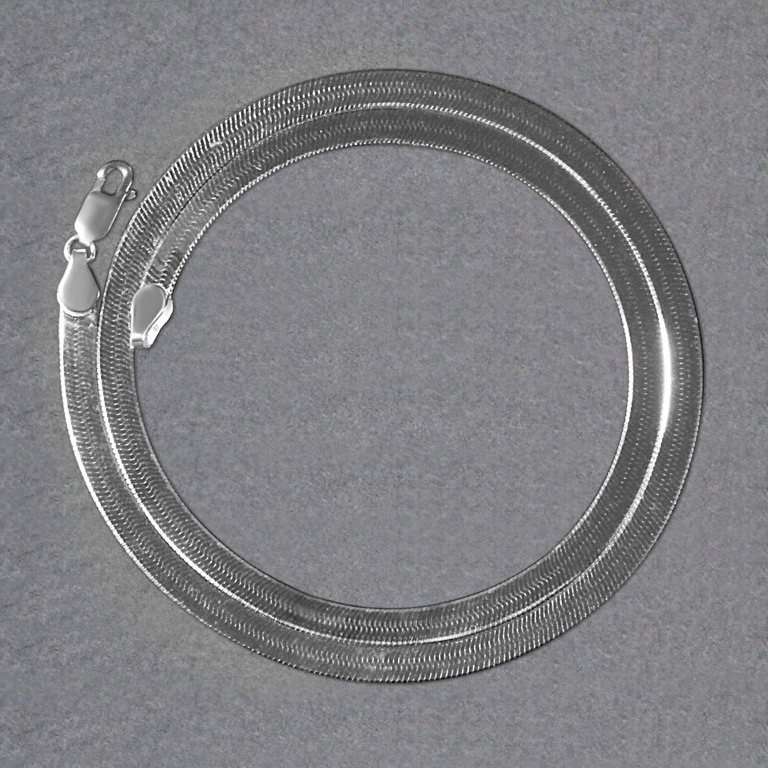 14k white gold super flex herringbone chain with a lobster clasp, coiled on a gray surface.