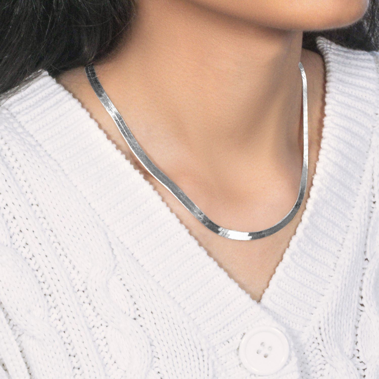 A 14k white gold super flex herringbone chain is worn around a person's neck.