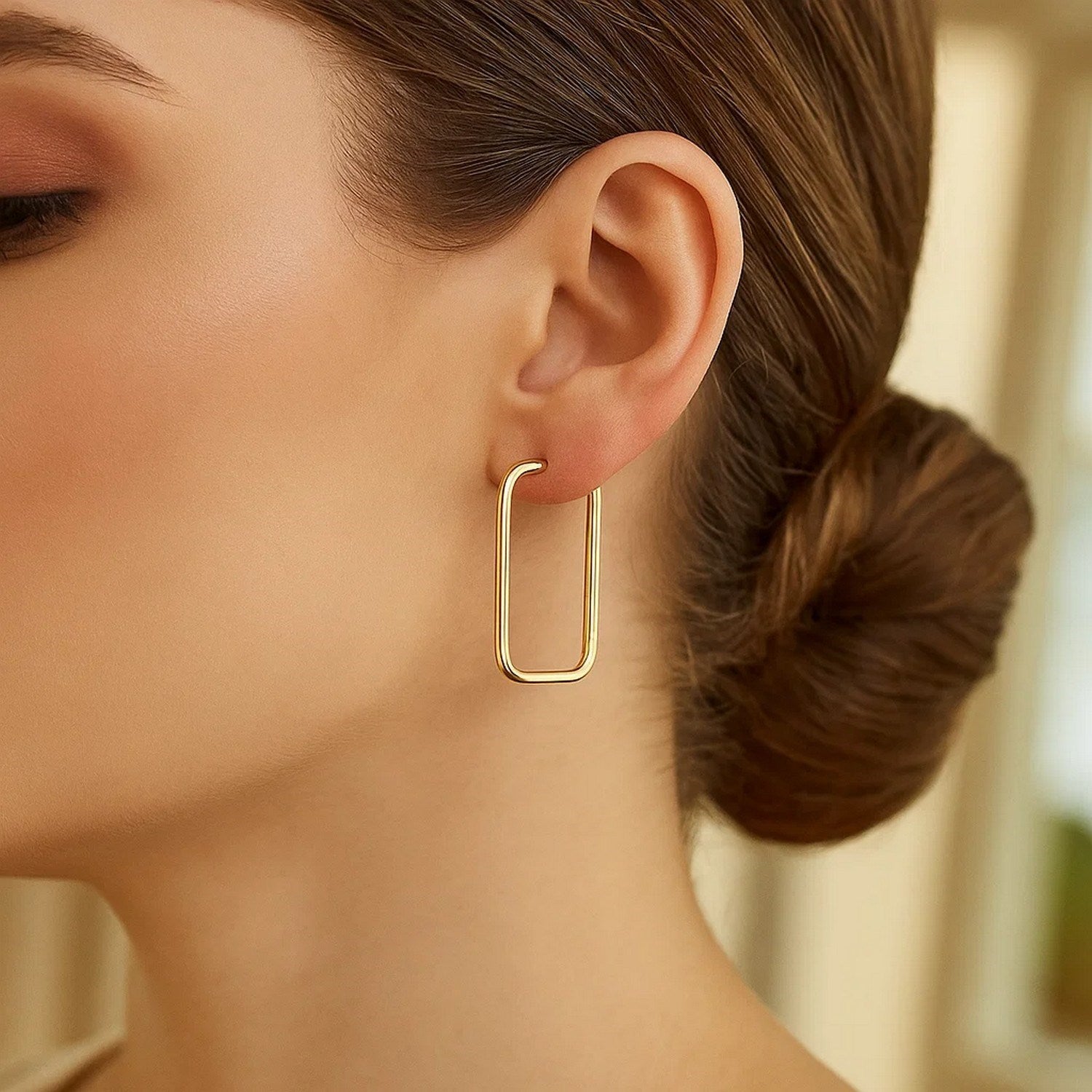 14k yellow gold endless rectangle hoop earrings are worn on a woman's ear.