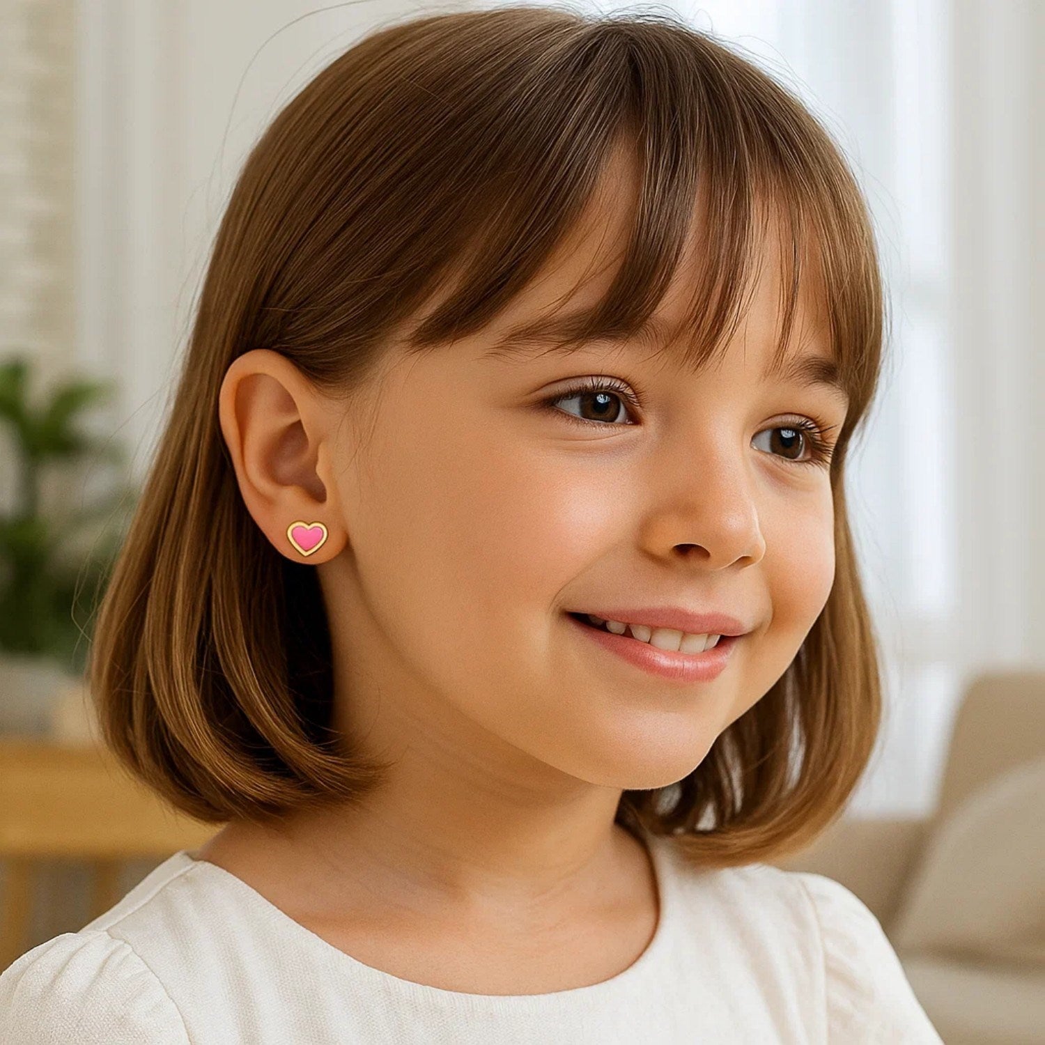 A young girl wears a single pink heart stud earring with a gold border.